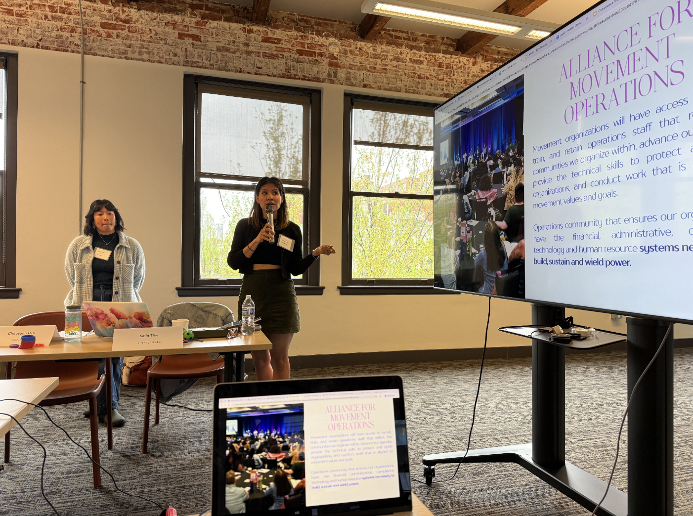 A participant in the compliance cohort holds a microphone next to a presentation  titled "alliance for movement operations"