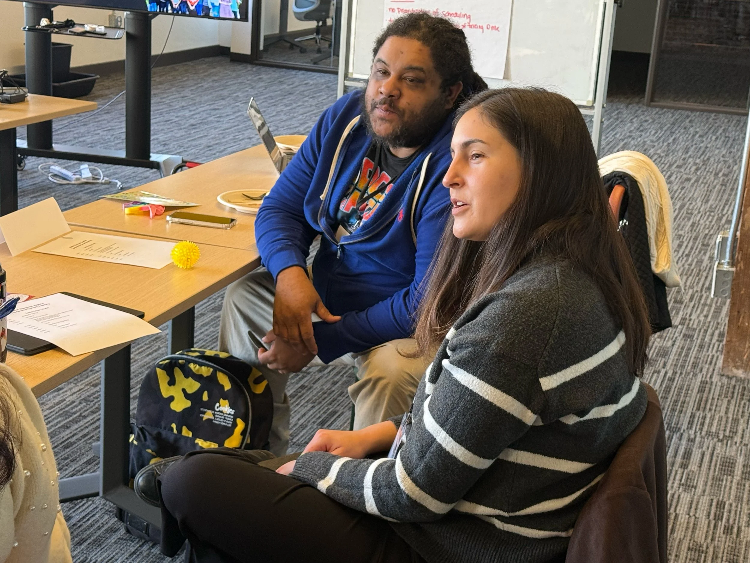 Two Cohort participants lean forward in their seats, one speaking.