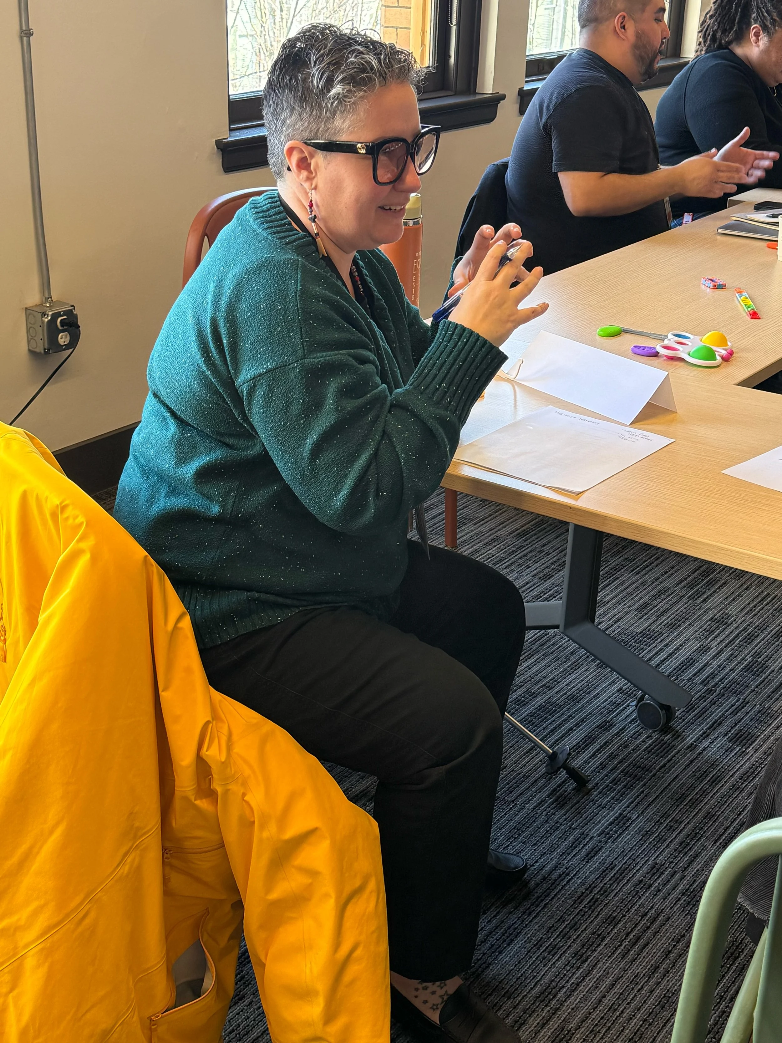 One Cohort participant sits, speaks, and gestures with their hands.