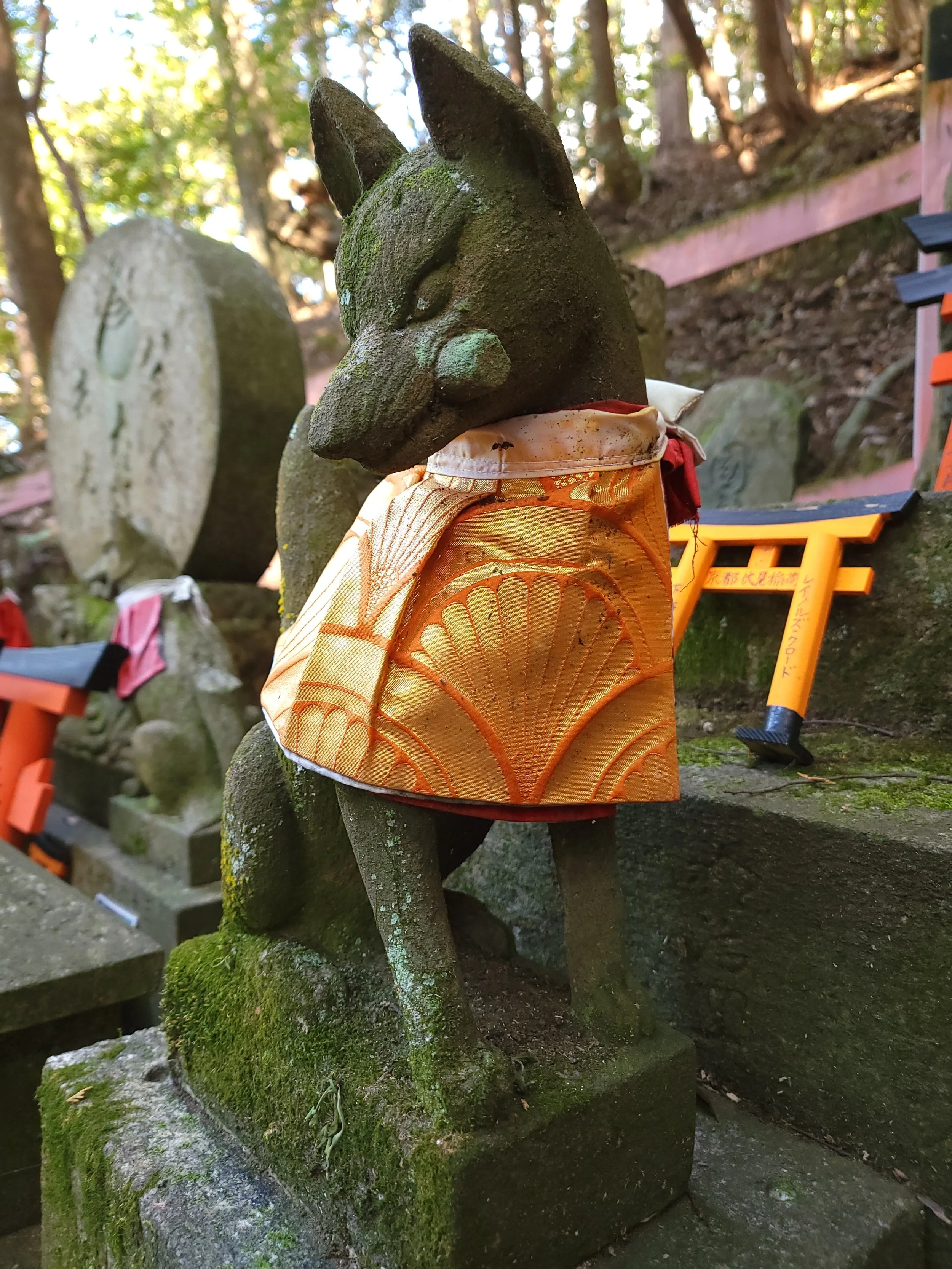 An Inari statue farther in the shrine grounds, up the mountain.  Moss gradually covering it.  You can see the layers of scarves placed around its neck.  Next time I go, I’m bringing and buying scarves for them!