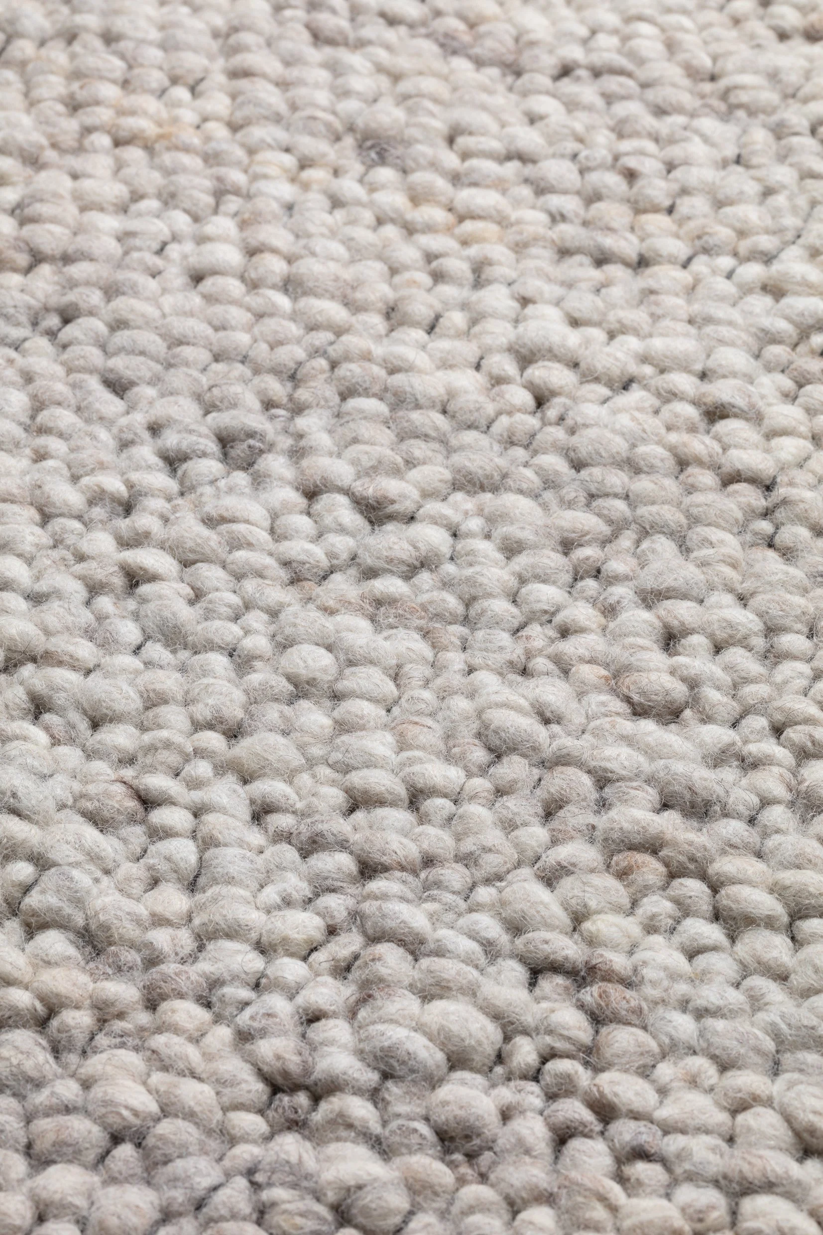 Close-up of beige textured carpet with small, rounded fibers.