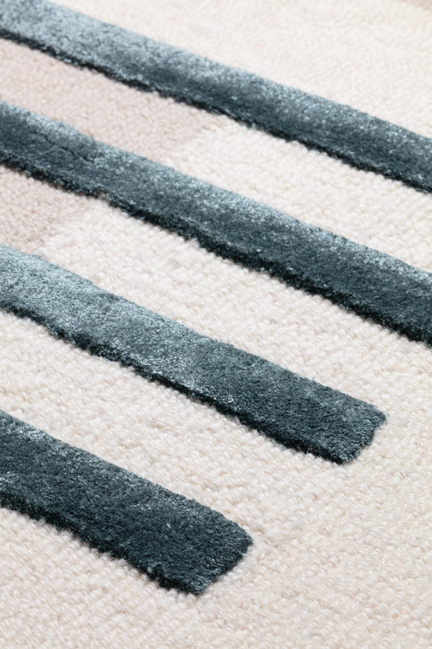 Close-up of a cream-colored rug with black and gray striped pattern.