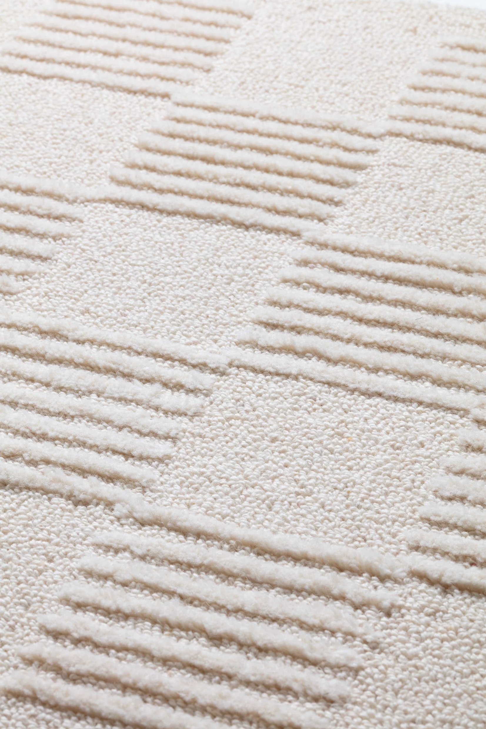 Close-up view of a textured white carpet with a geometric pattern of grooves and raised areas.