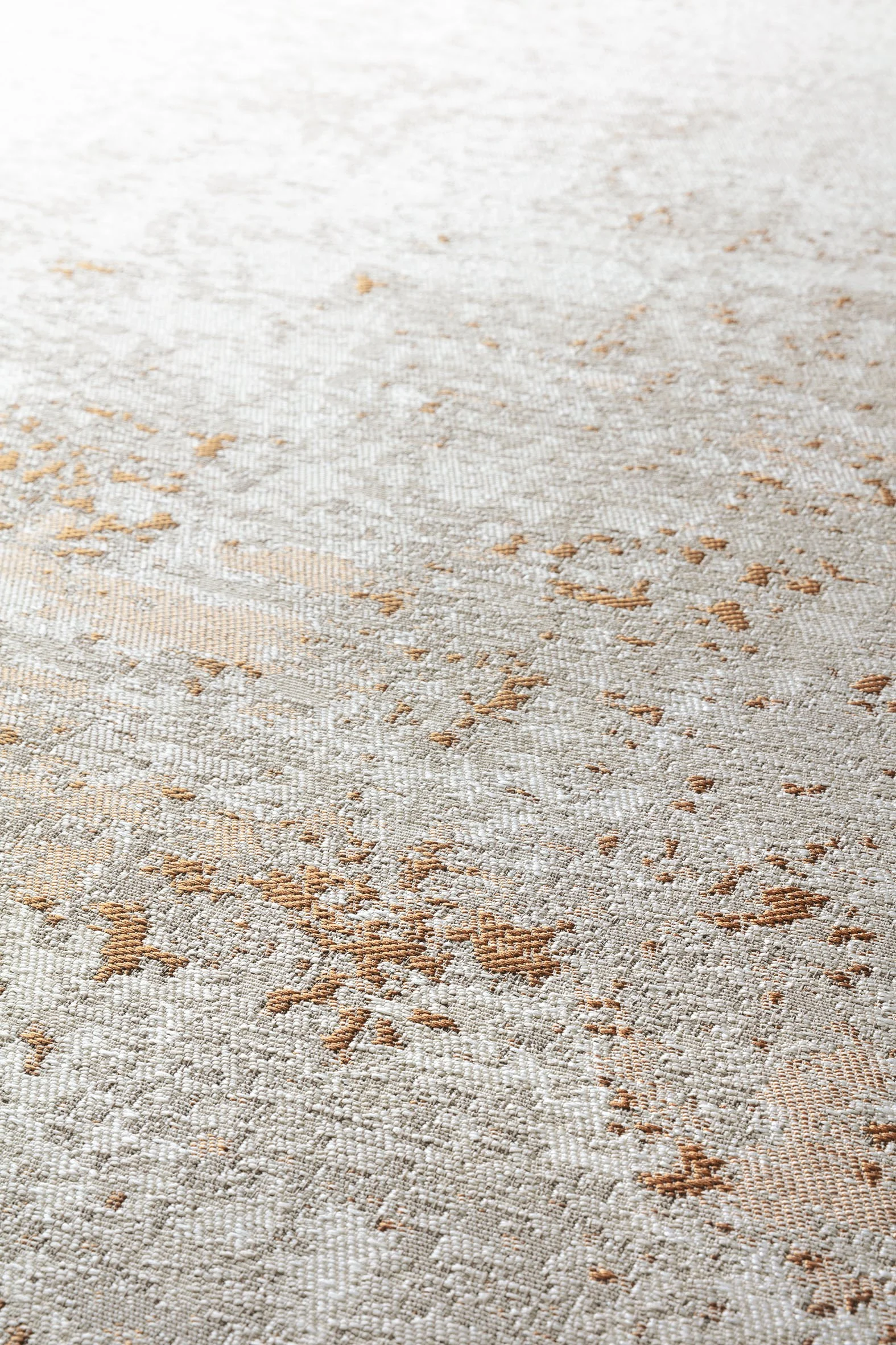 Close-up of a beige and light brown patterned rug with intricate designs.