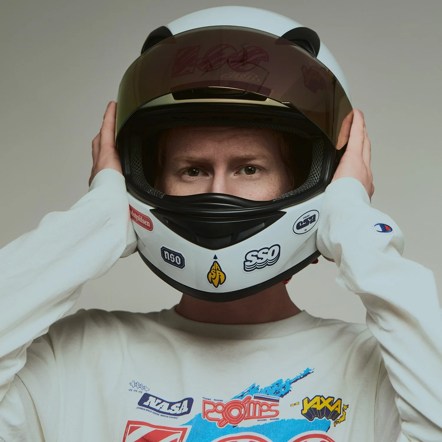 Model wearing Supercluster graphic long sleeve and white racing helmet photographed for apparel campaign.