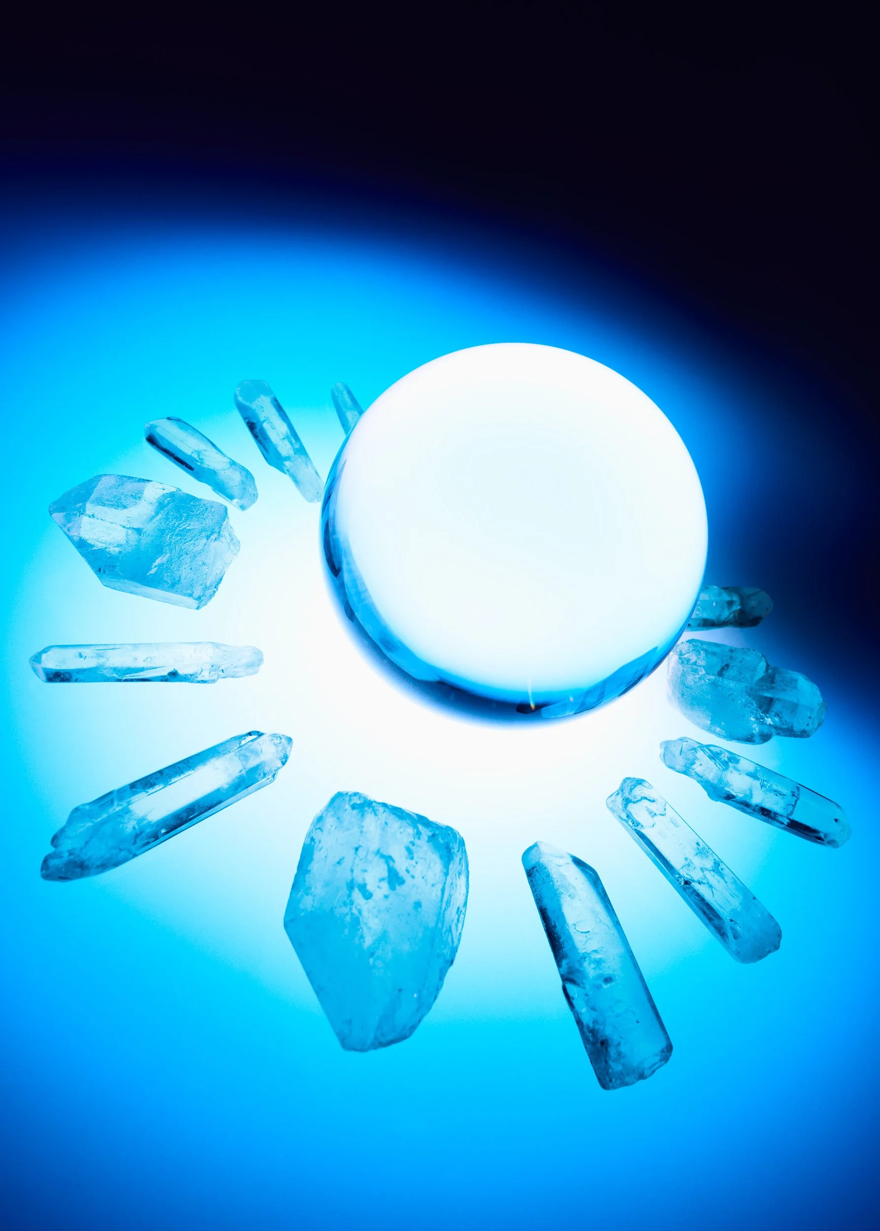Glowing crystal sphere surrounded by blue quartz crystals photographed for GrandArmy 15-year Crystal Anniversary celebration.