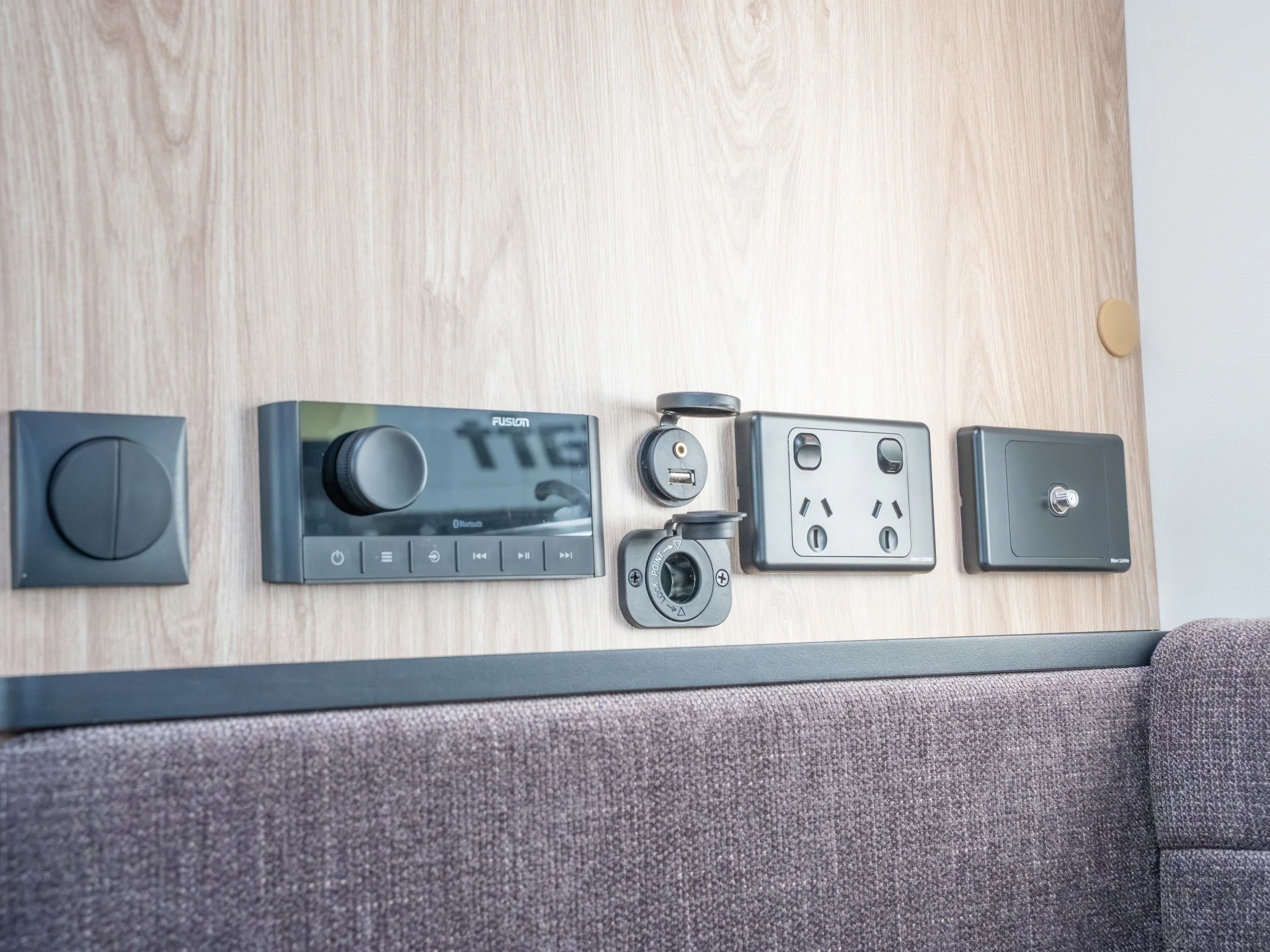 Electrical outlets and devices mounted on a wooden wall with carpeted surface below.