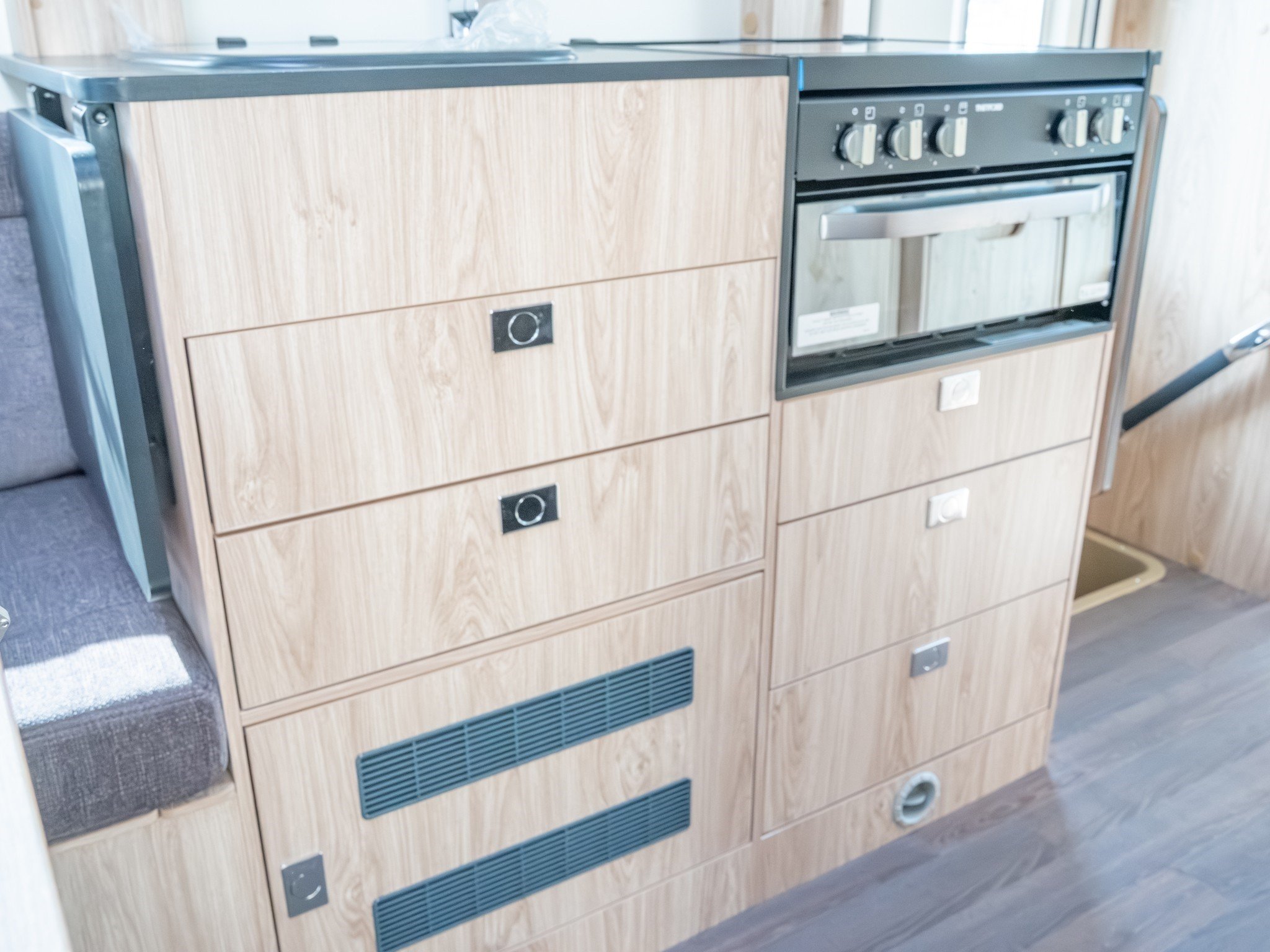 A built-in oven and a wooden storage cabinet in a kitchen or similar space.