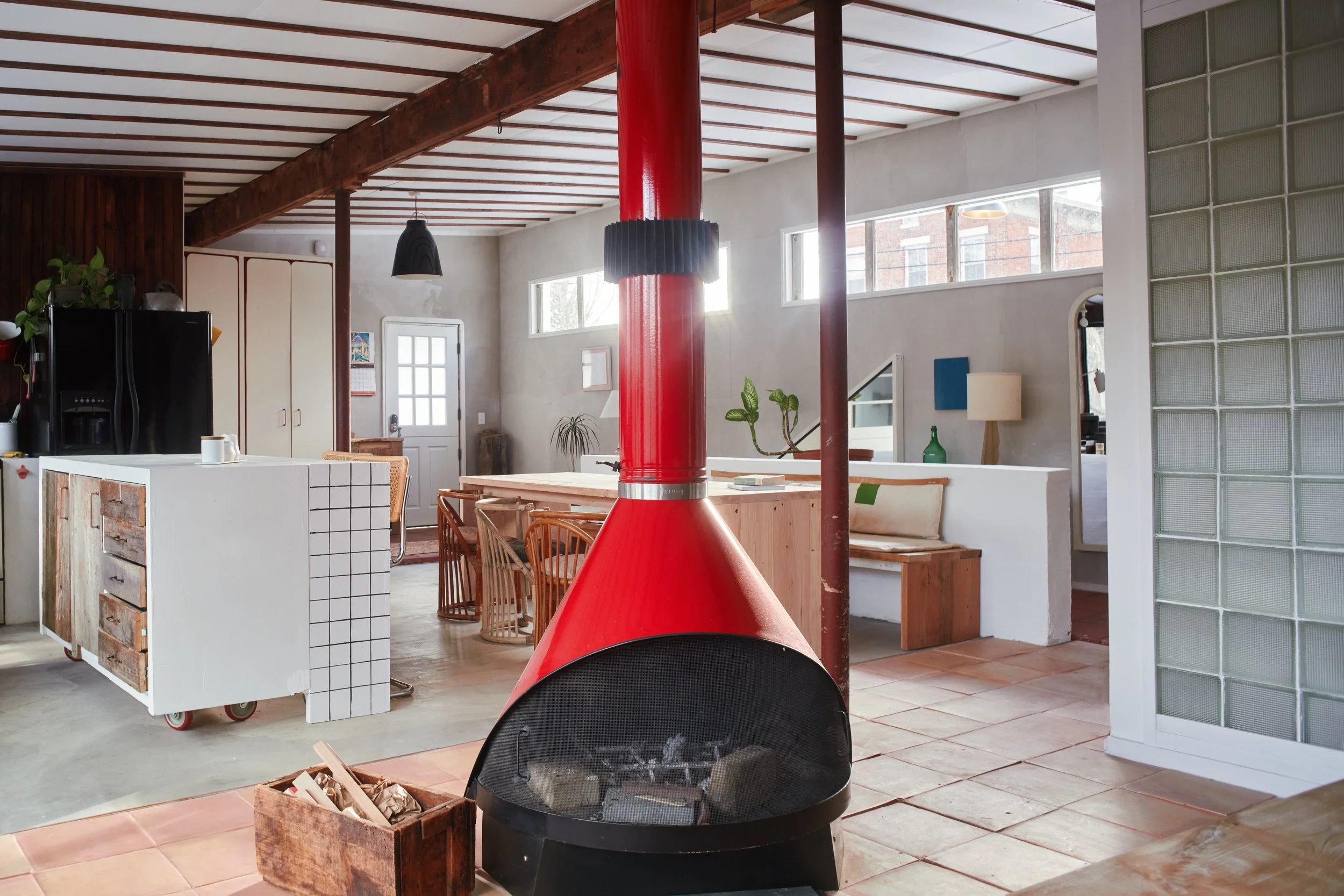 Open-concept kitchen and living space with a red fireplace in the center, dining table, and modern decor.