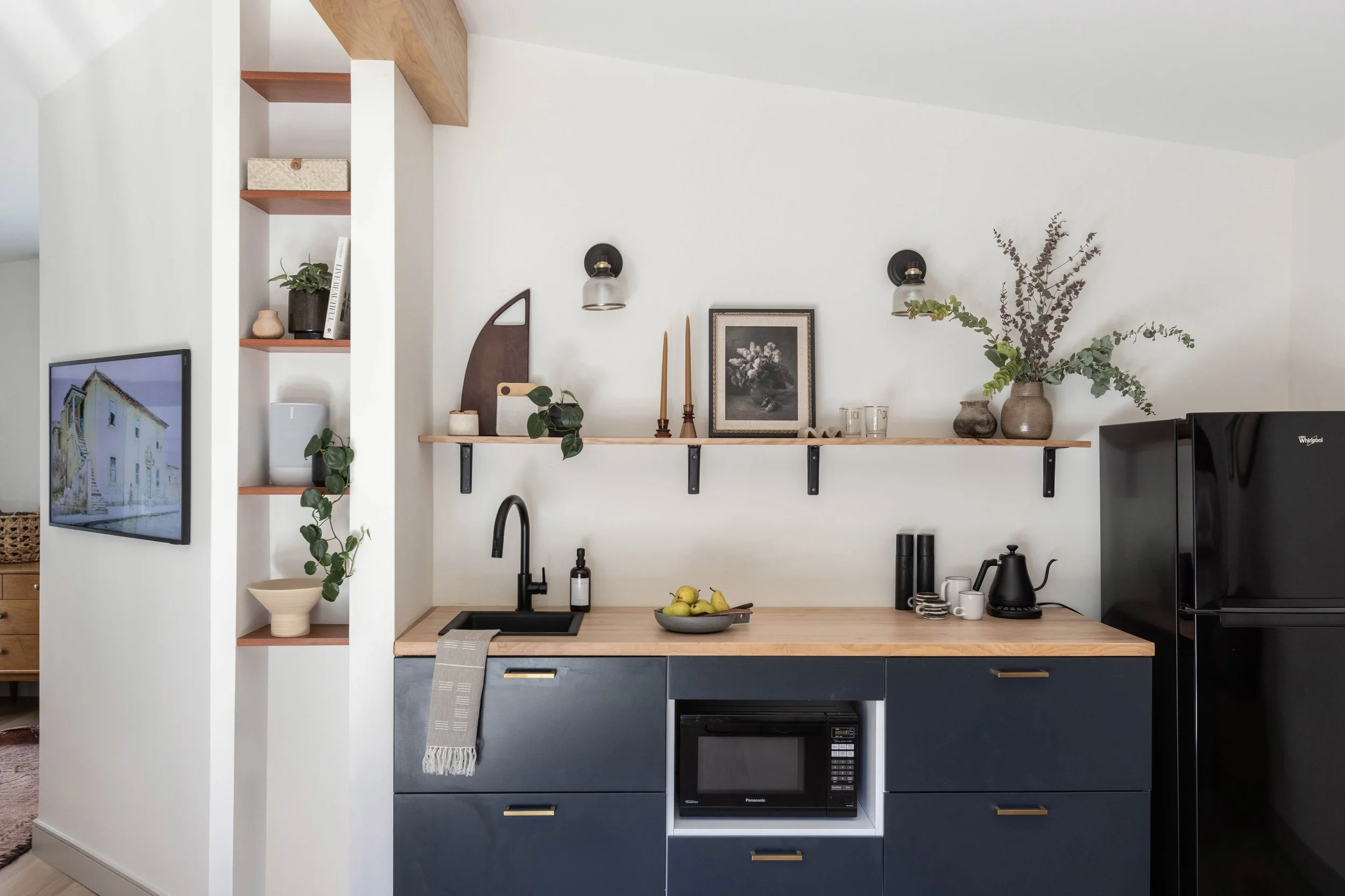 Kitchenette with storage nook, floating shelves and wall mounted tv