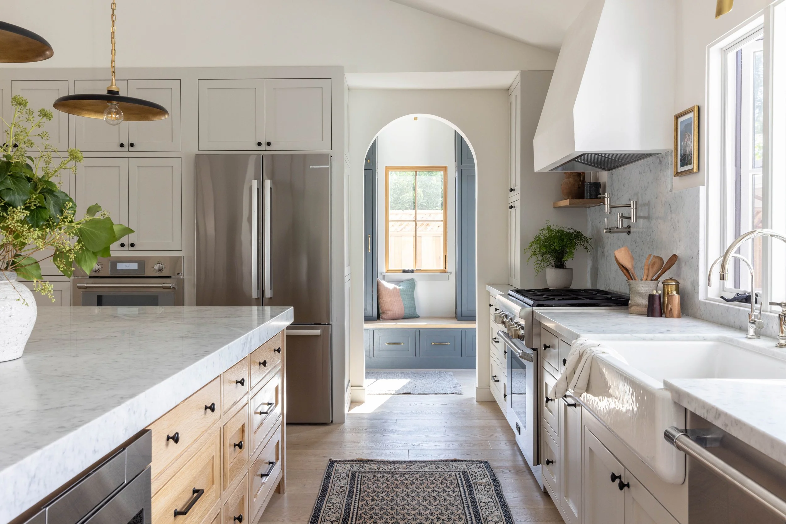 kitchen site profile with Thermador range and smart oven, microwave drawer, custom range hood and arch entry to the mood room