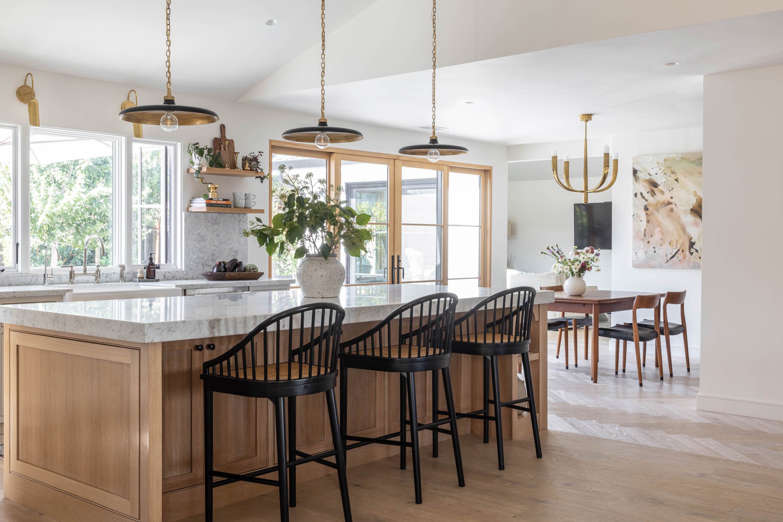 Kitchen island with pendant lights, dining room with chandelier, picture window and sliding glass door
