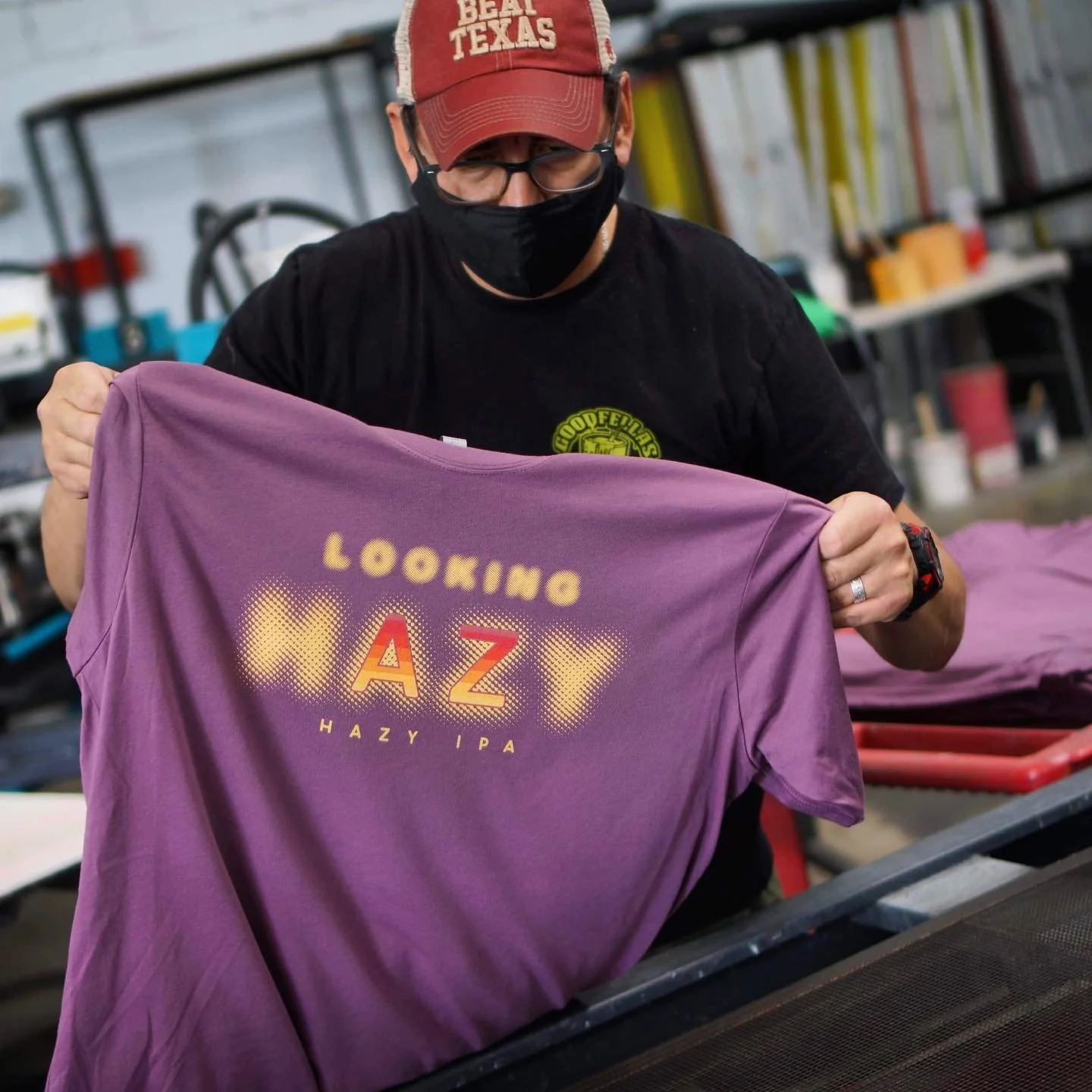 A Goodfellas Merch employee holds up a tshirt with the brand Hazy IPA