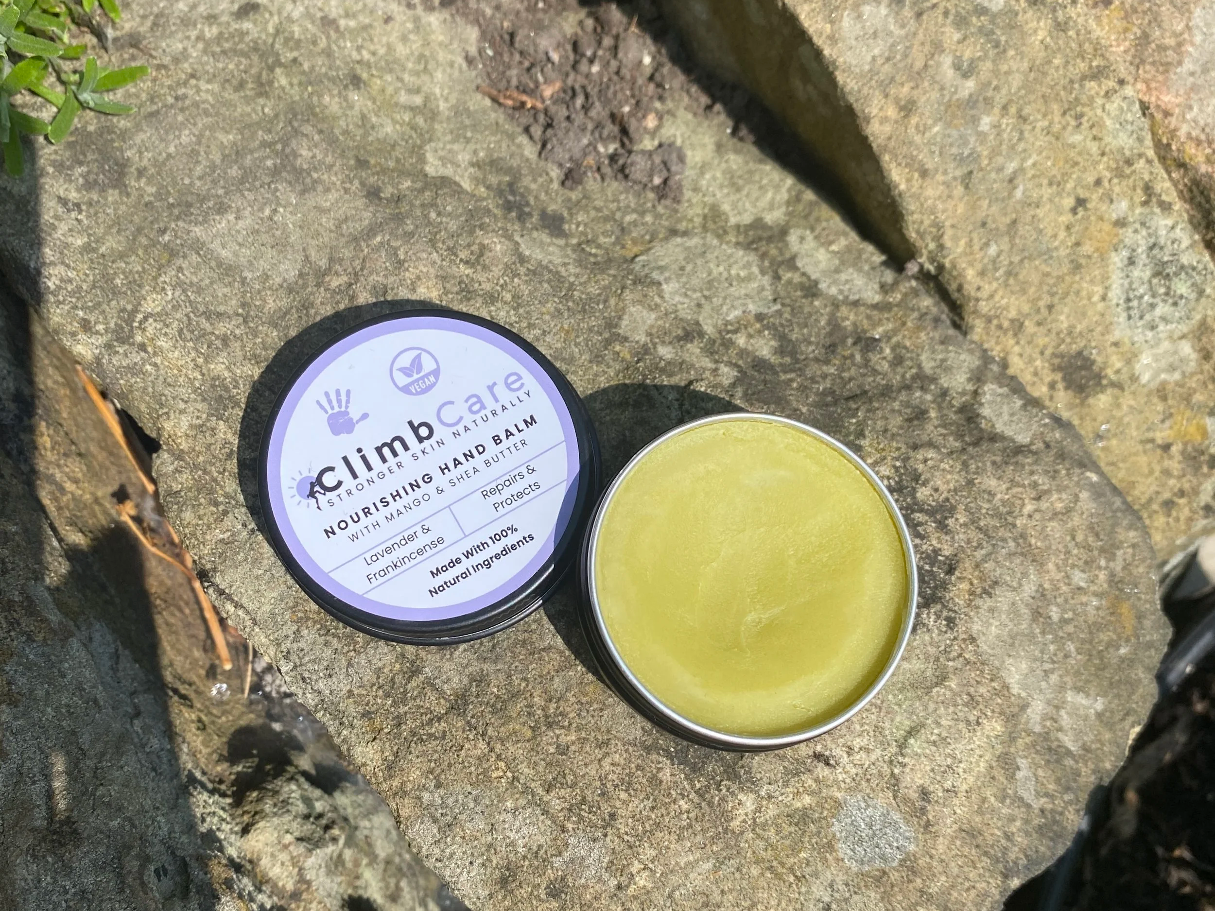 Open tin of ClimbCare vegan hand balm on a stone wall