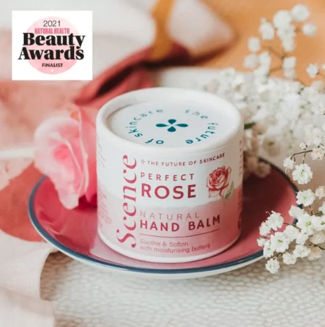 Scence perfect rose hand balm packaging on a saucer surrounded by flowers