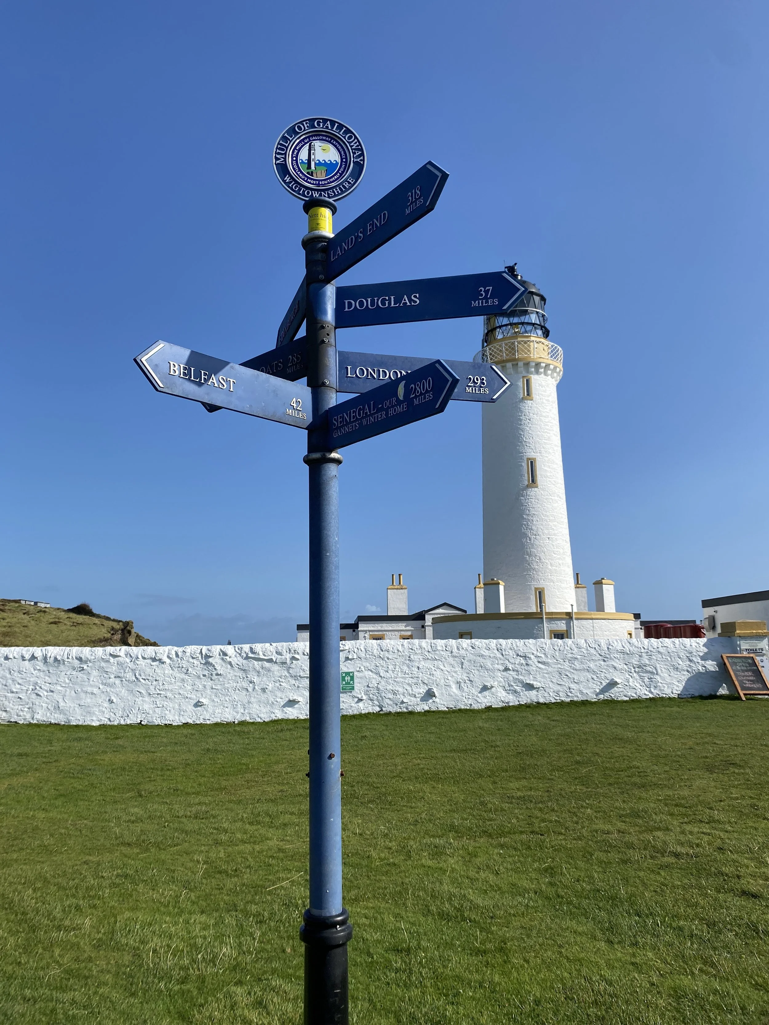 Signpost at the Mull of Galloway, with lighthouse behind