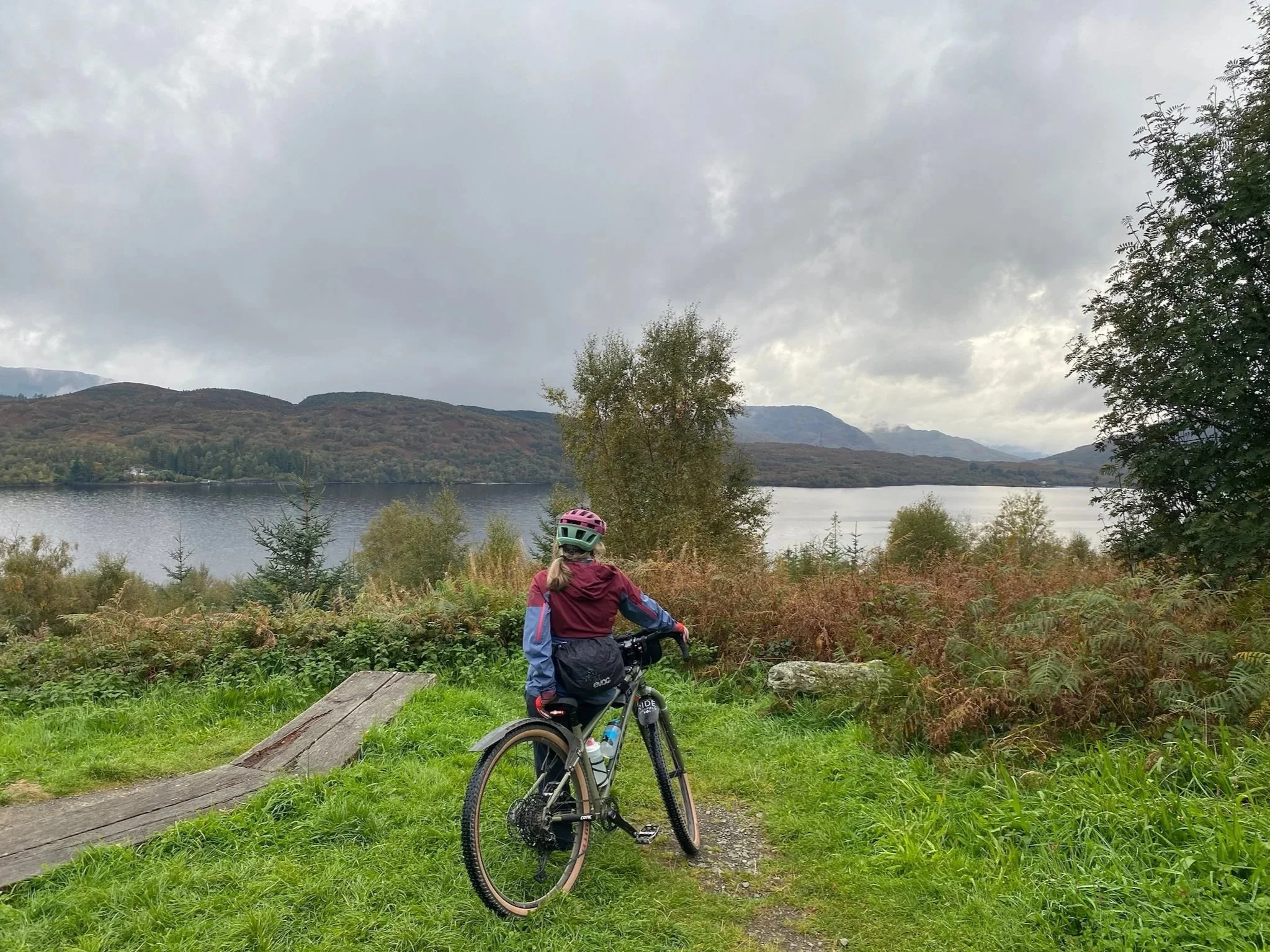 Person leaning on a bike looking out over Loch Katrine, Scotland