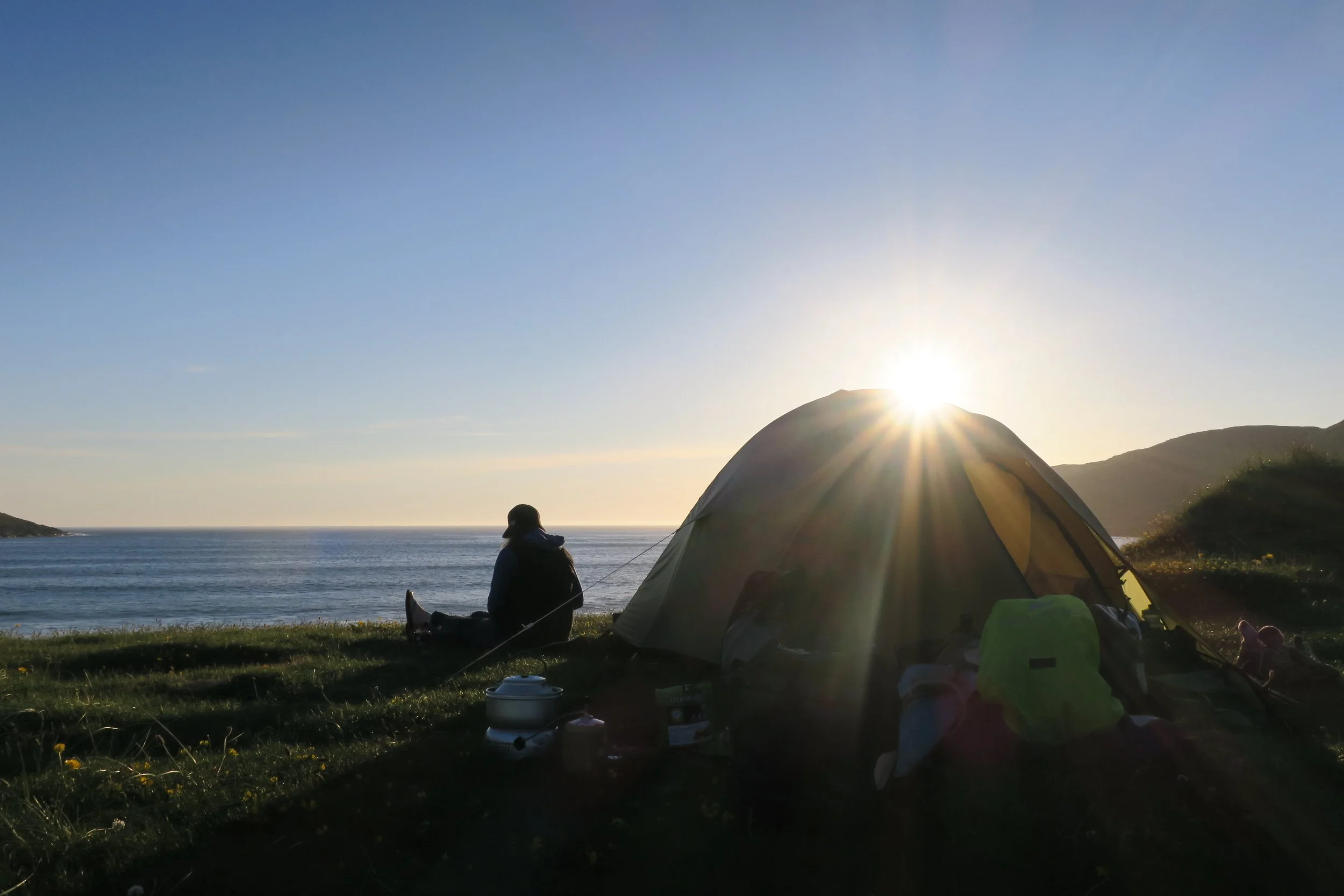 Sitting outside a tent, watching the sun go down over the beach on Vatersay