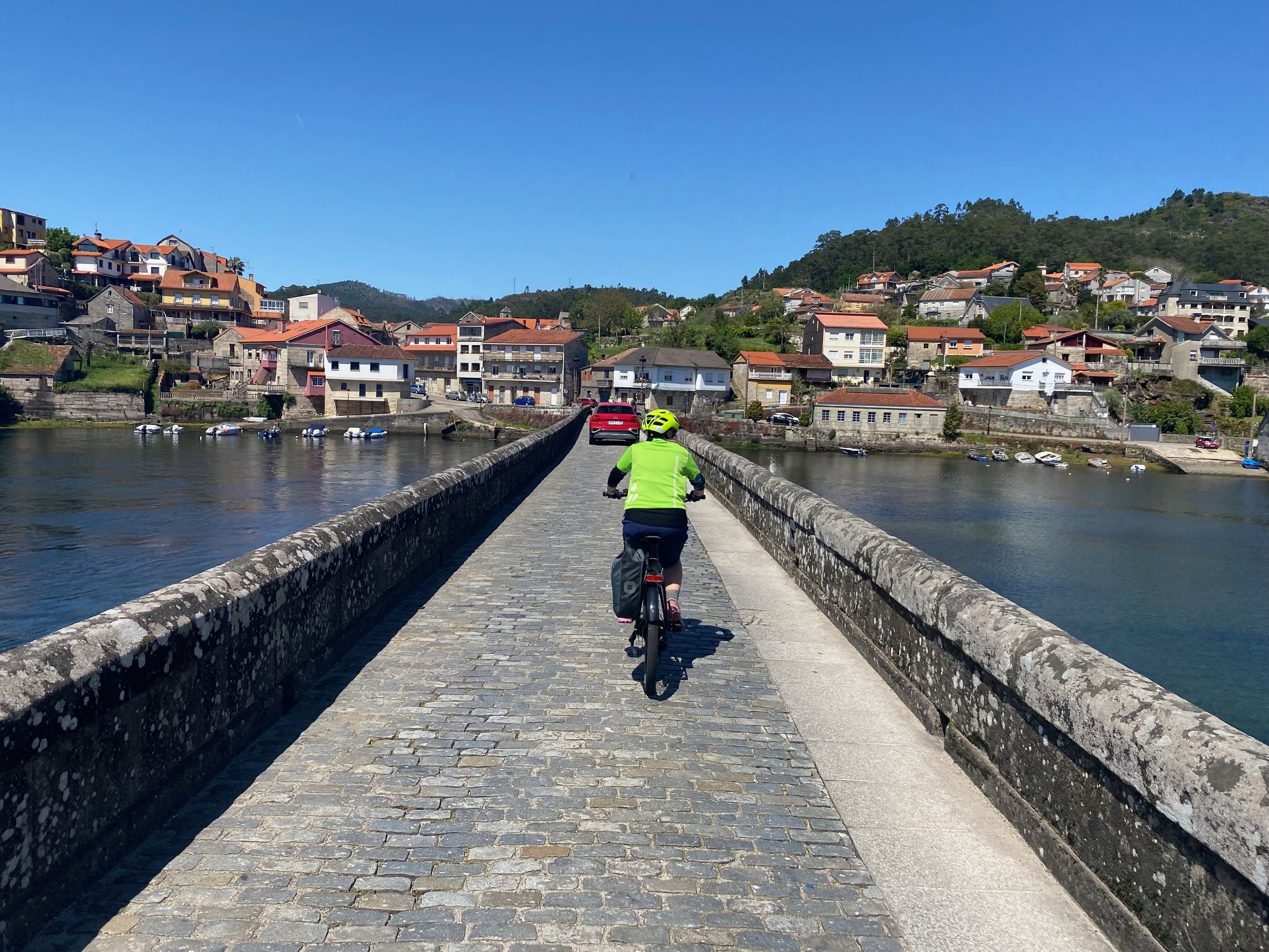 Cycling across the historic one-lane Ponte Sampaio, Pontevedra, Spain