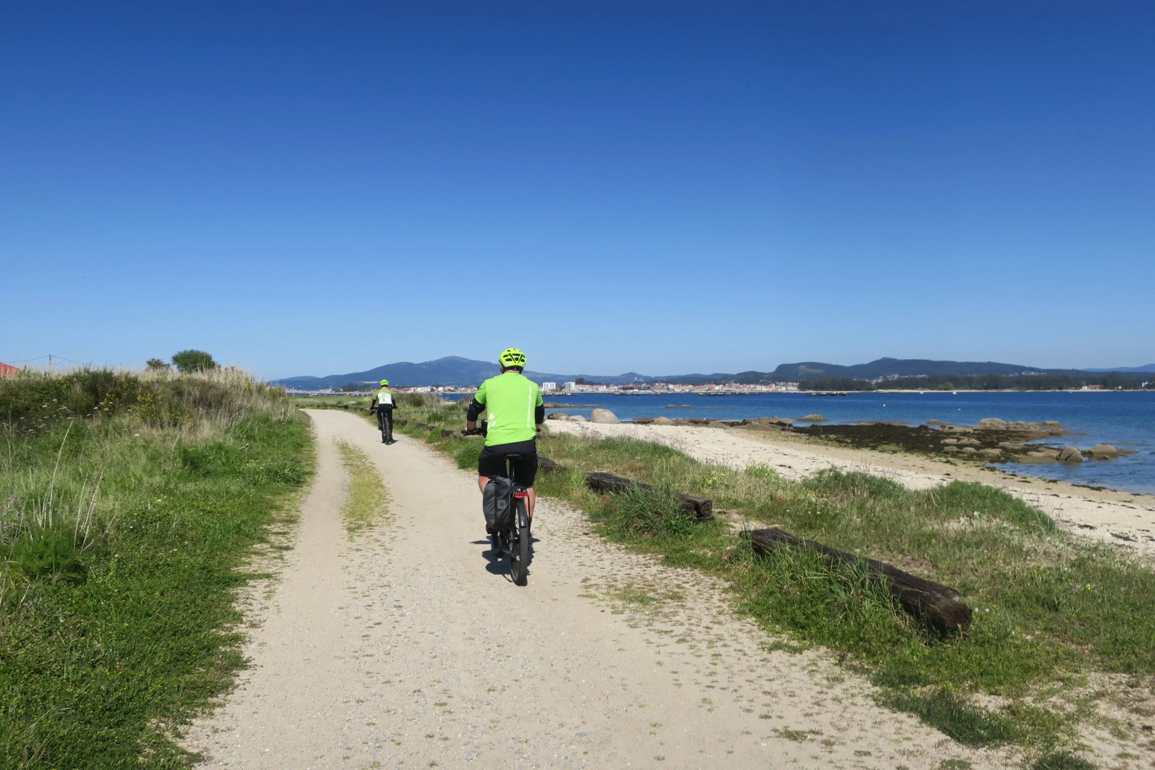 Two cyclists alongside sandy beach on the Illa da Arousa, Galicia, Spain