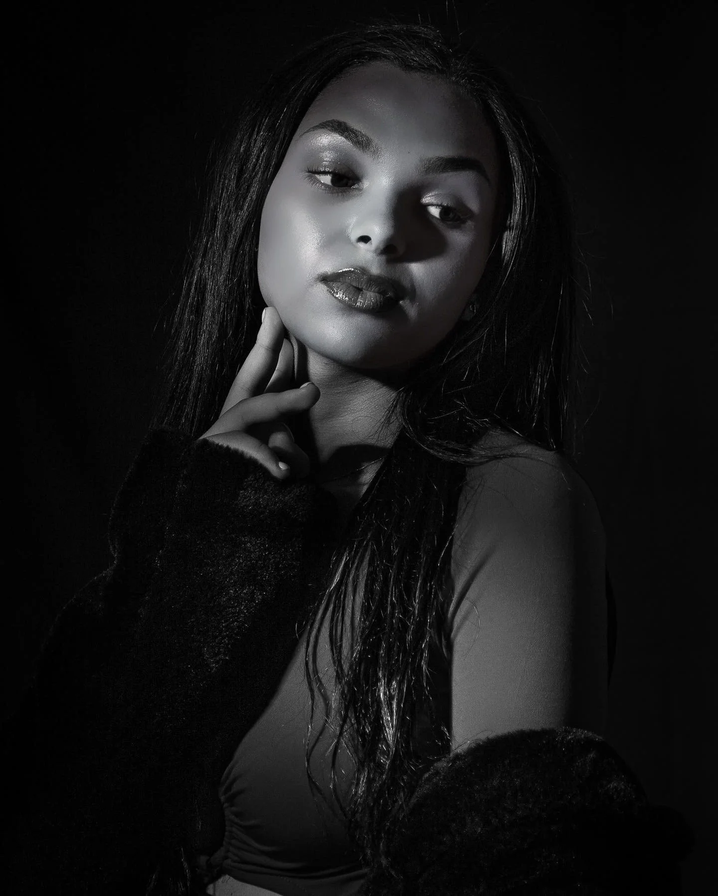 Black and white portrait of a woman with long hair, posing with her hand near her chin.