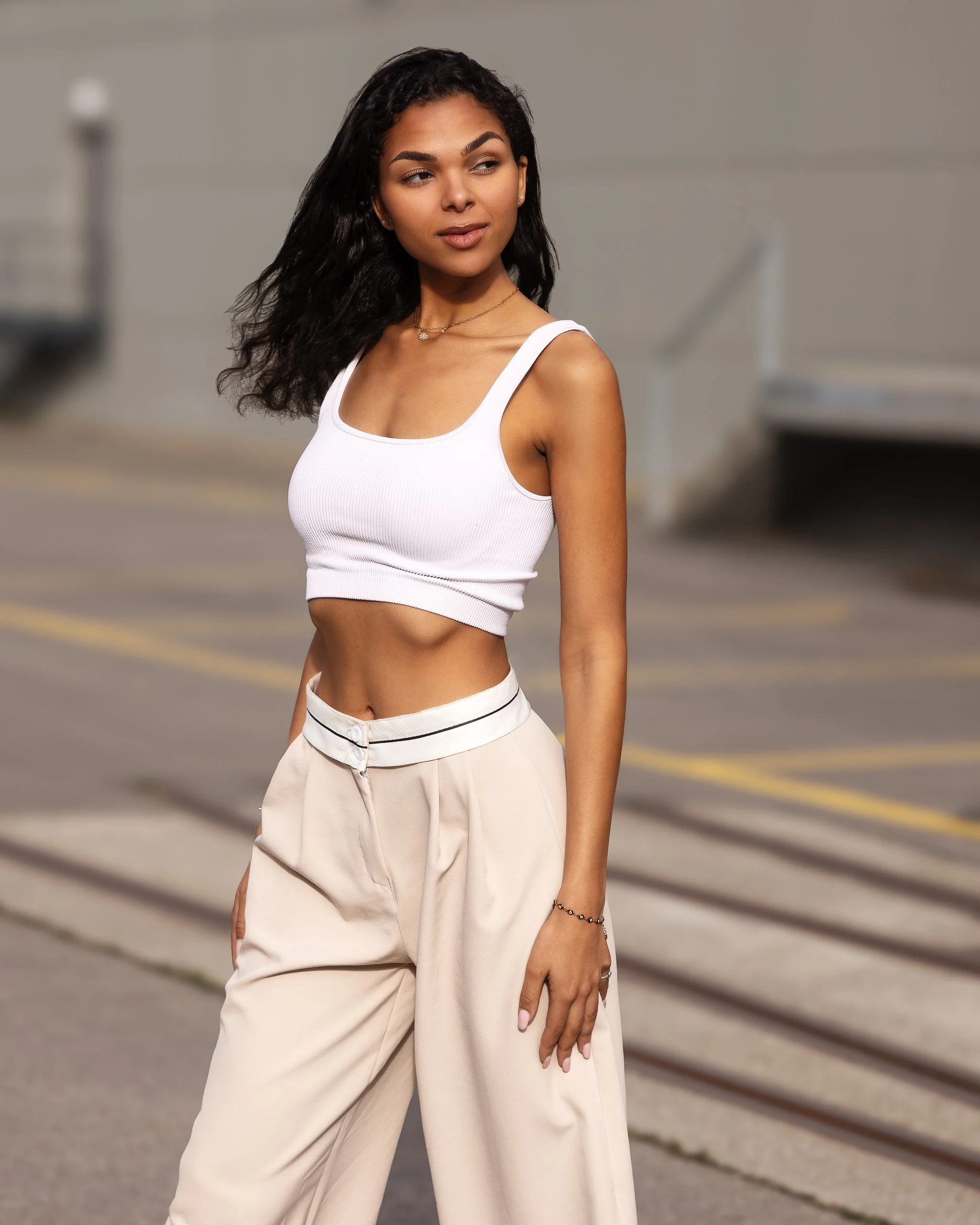 Woman in a white crop top and beige pants outdoors.