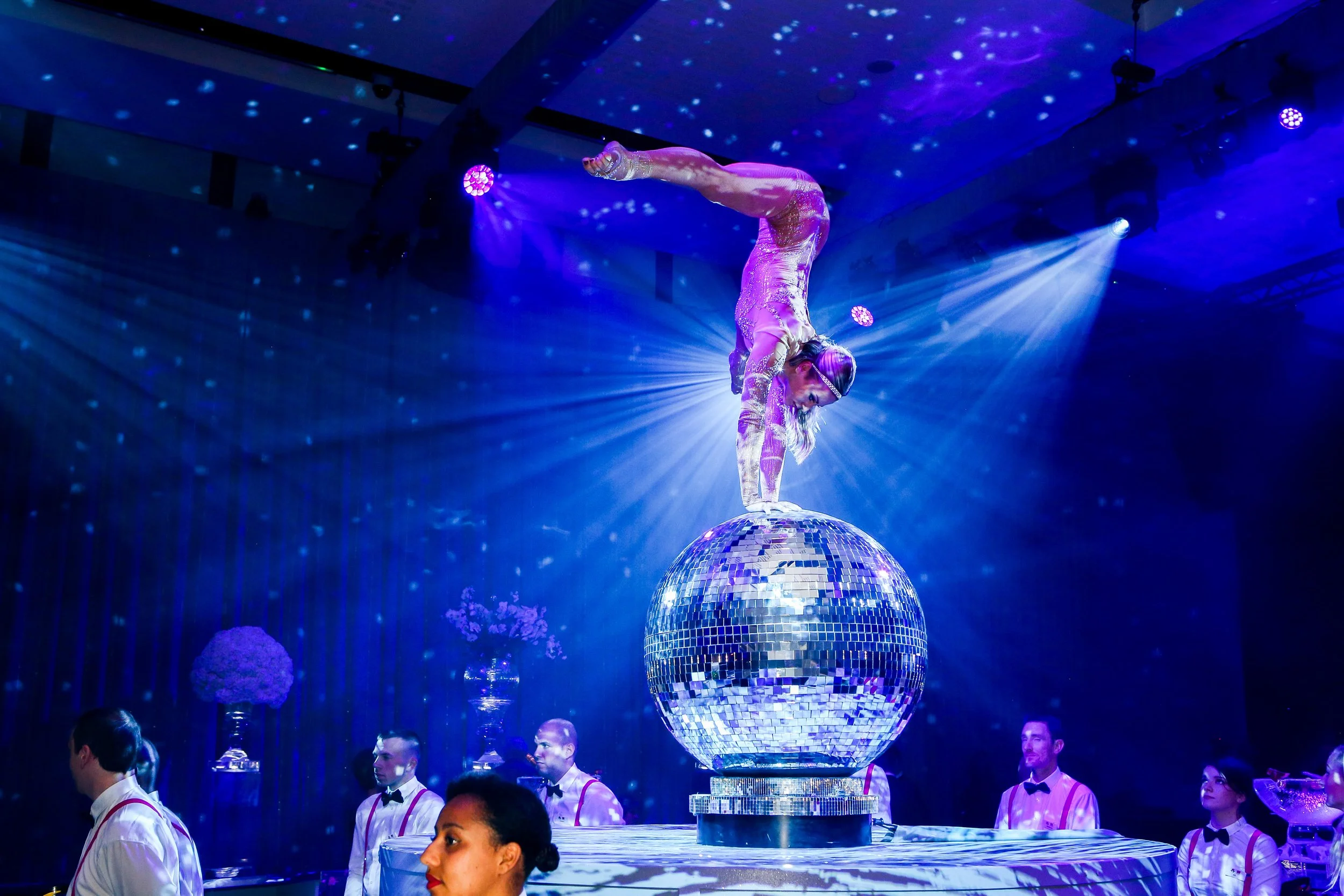 acrobat balances on glitter ball