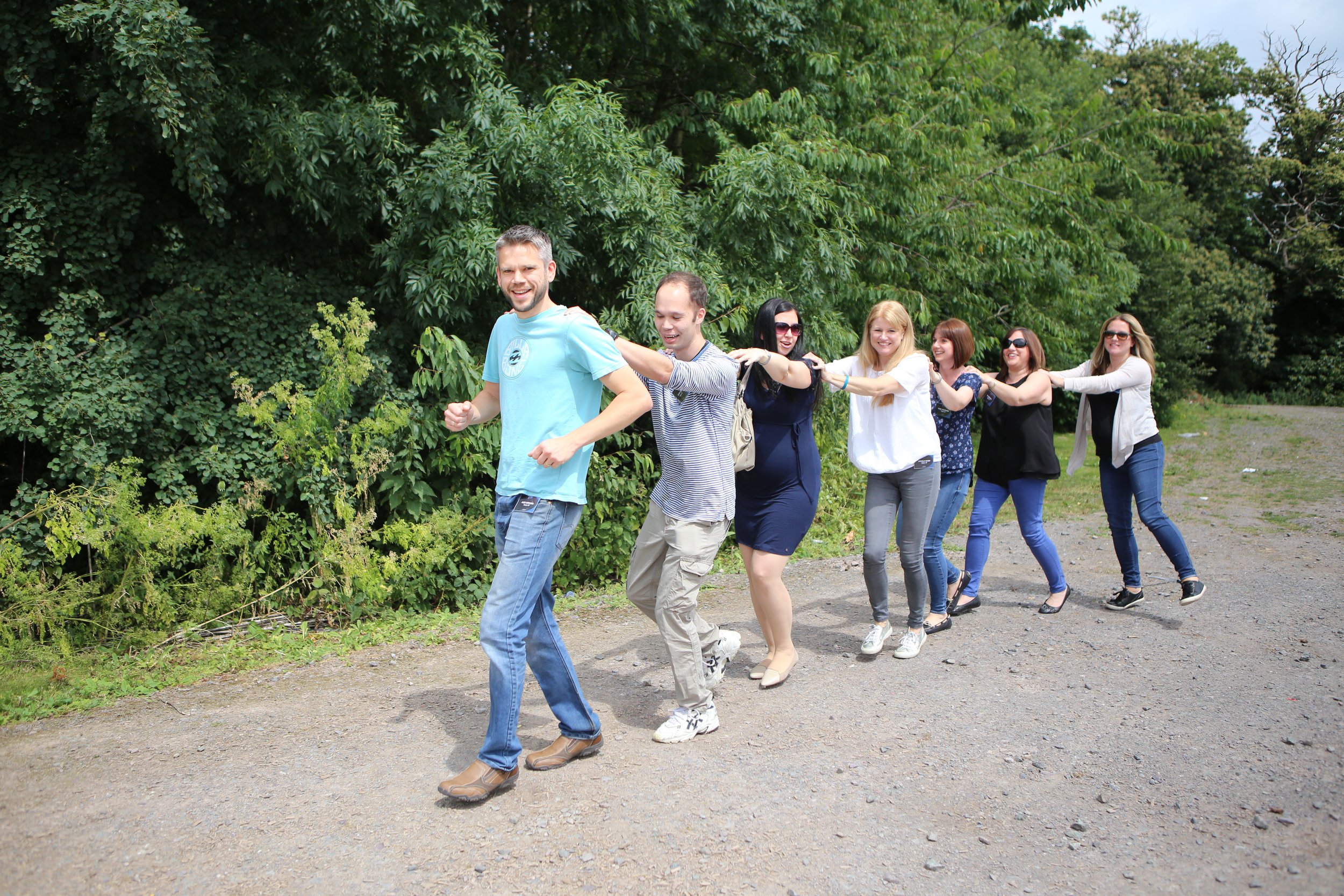 A group of people forming a conga line outdoors.