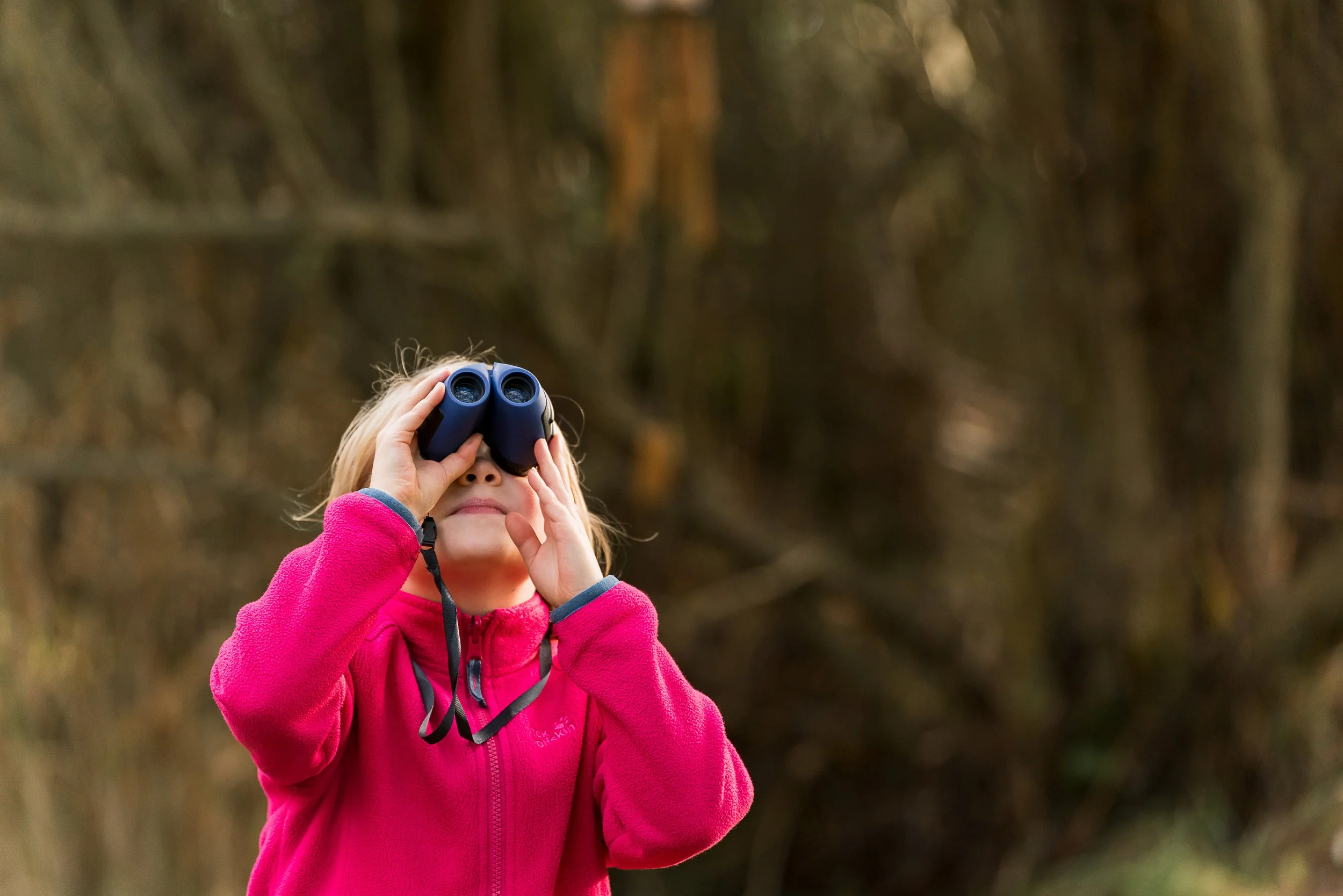 Girl with binoculars looking upwards