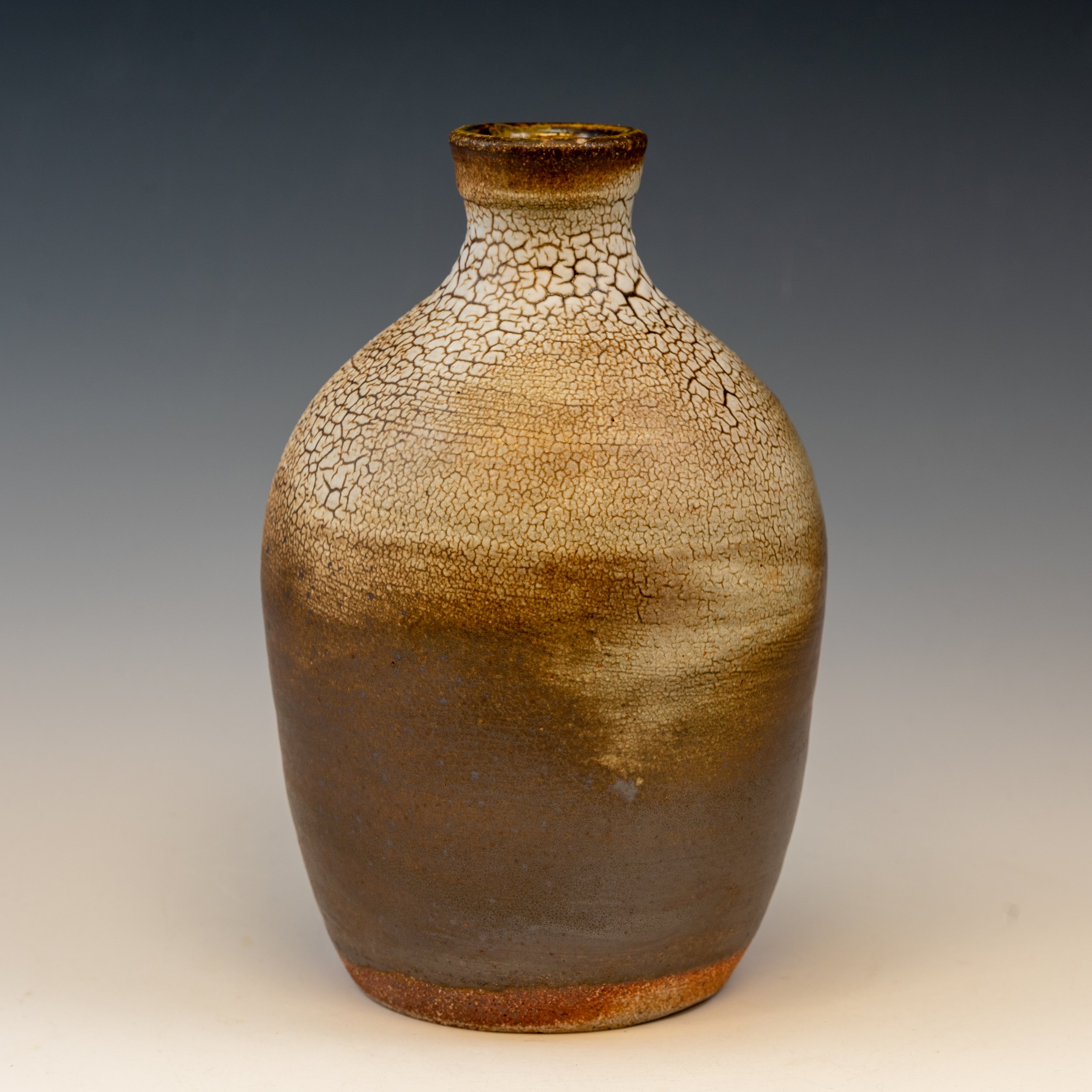 A ceramic vase with a crackle glaze pattern, brownish top, and gradient reddish-brown base, against a gradient grey background.