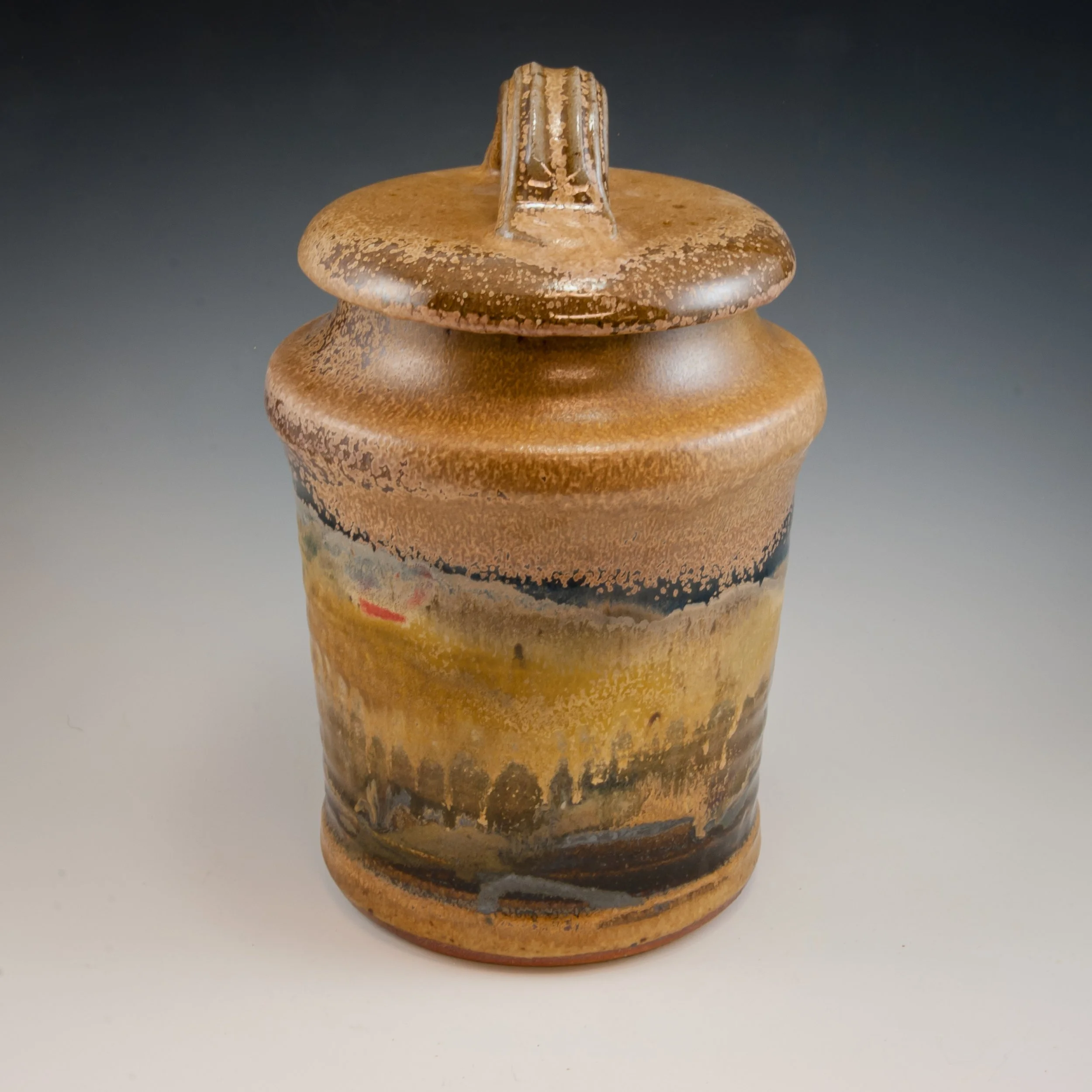 Close-up of a ceramic vase with earthy brown and black glaze, featuring a textured, speckled surface and a small, narrow neck.
