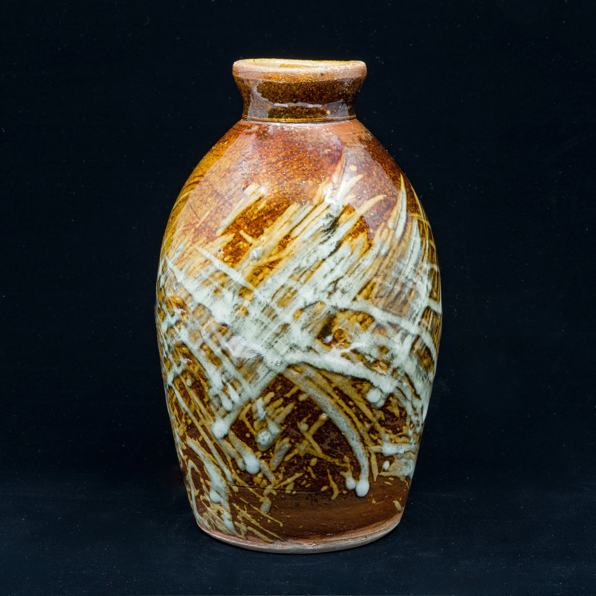 A ceramic vase with a brown and cream marbled design and a textured, unglazed top against a black background.