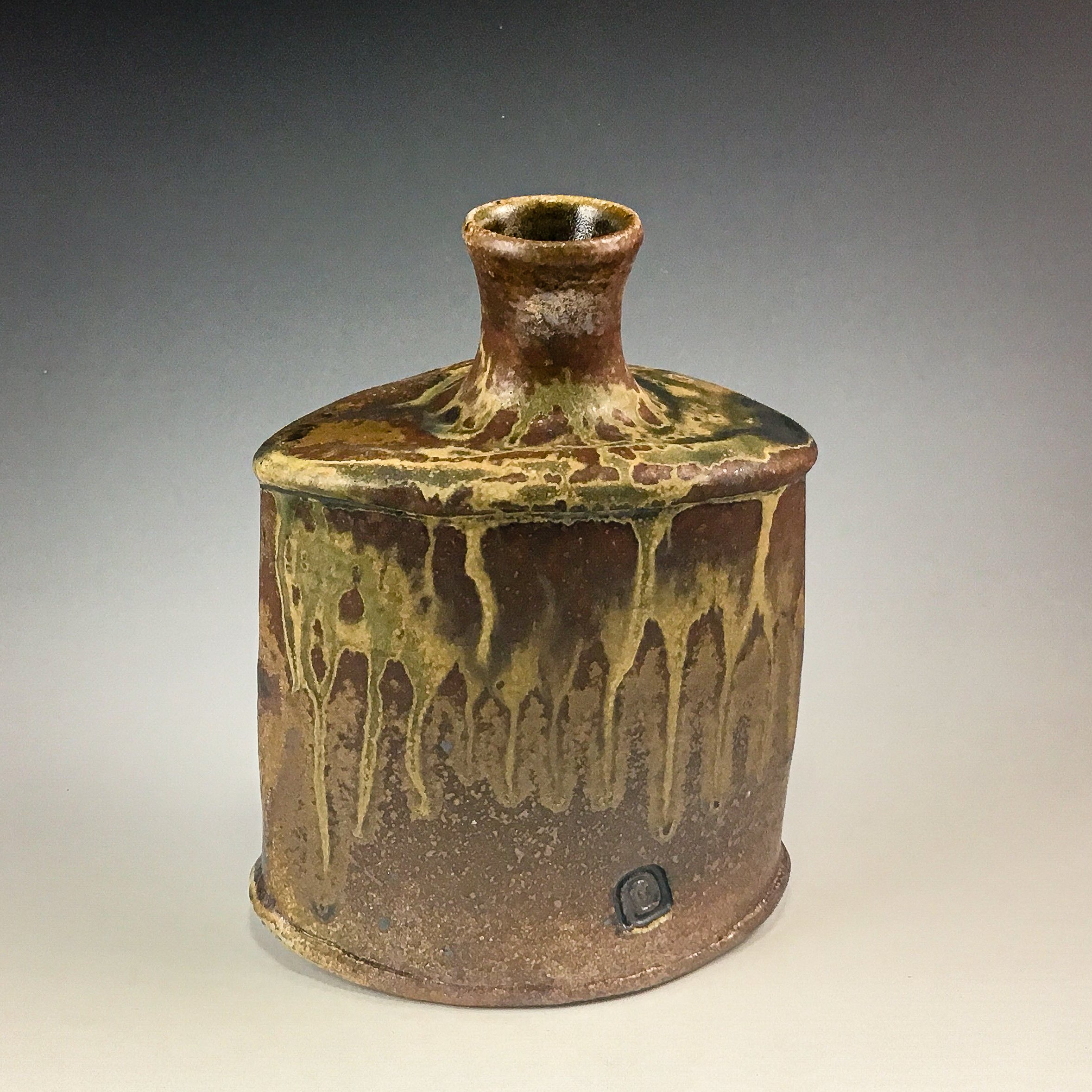 Ancient pottery vessel with a narrow neck and decorated with painted patterns, placed on a plain surface against a gray background.