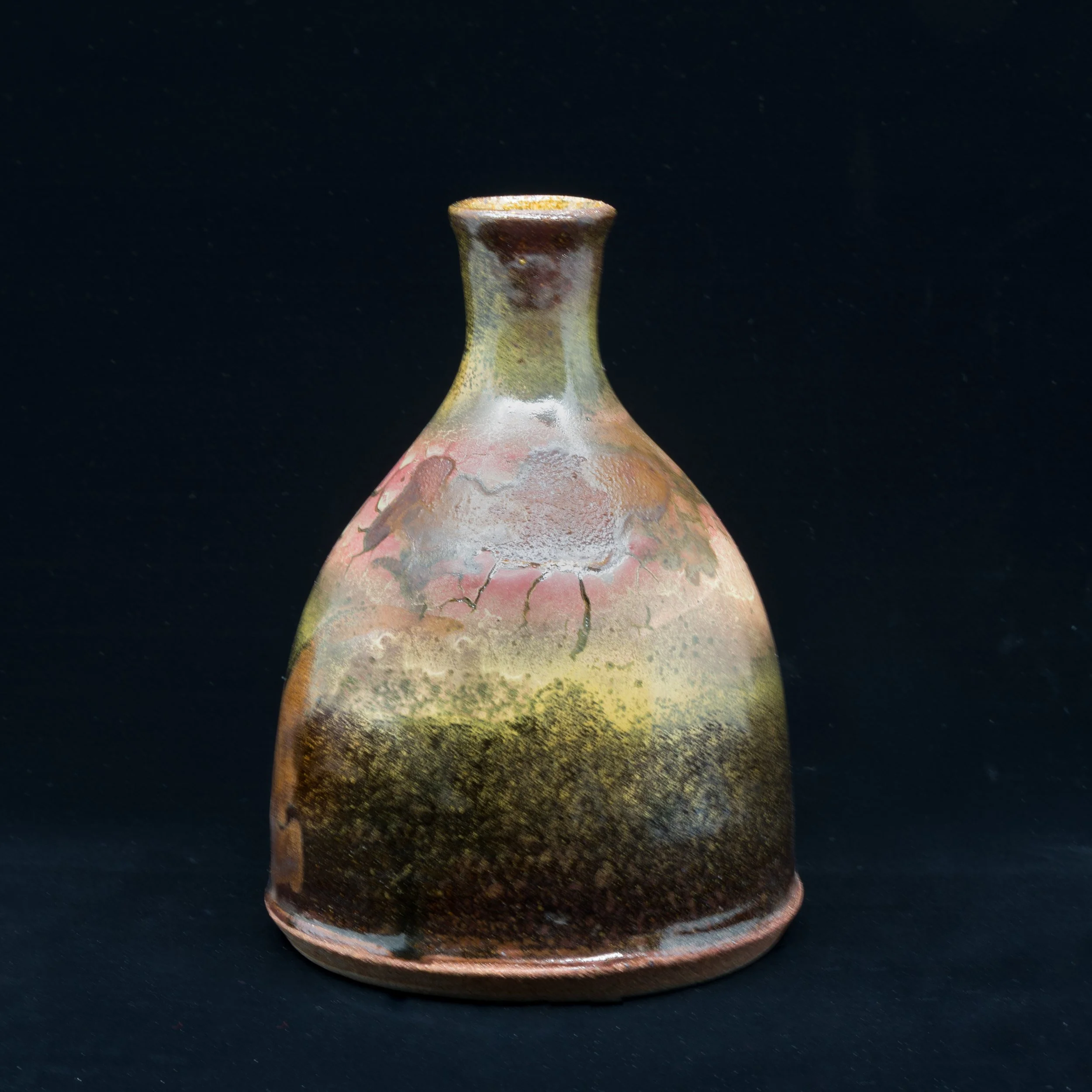 Close-up of a ceramic vase with a narrow neck and a wide, rounded body, featuring a crackle glaze with earthy tones of brown, beige, and reddish hues, set against a black background.