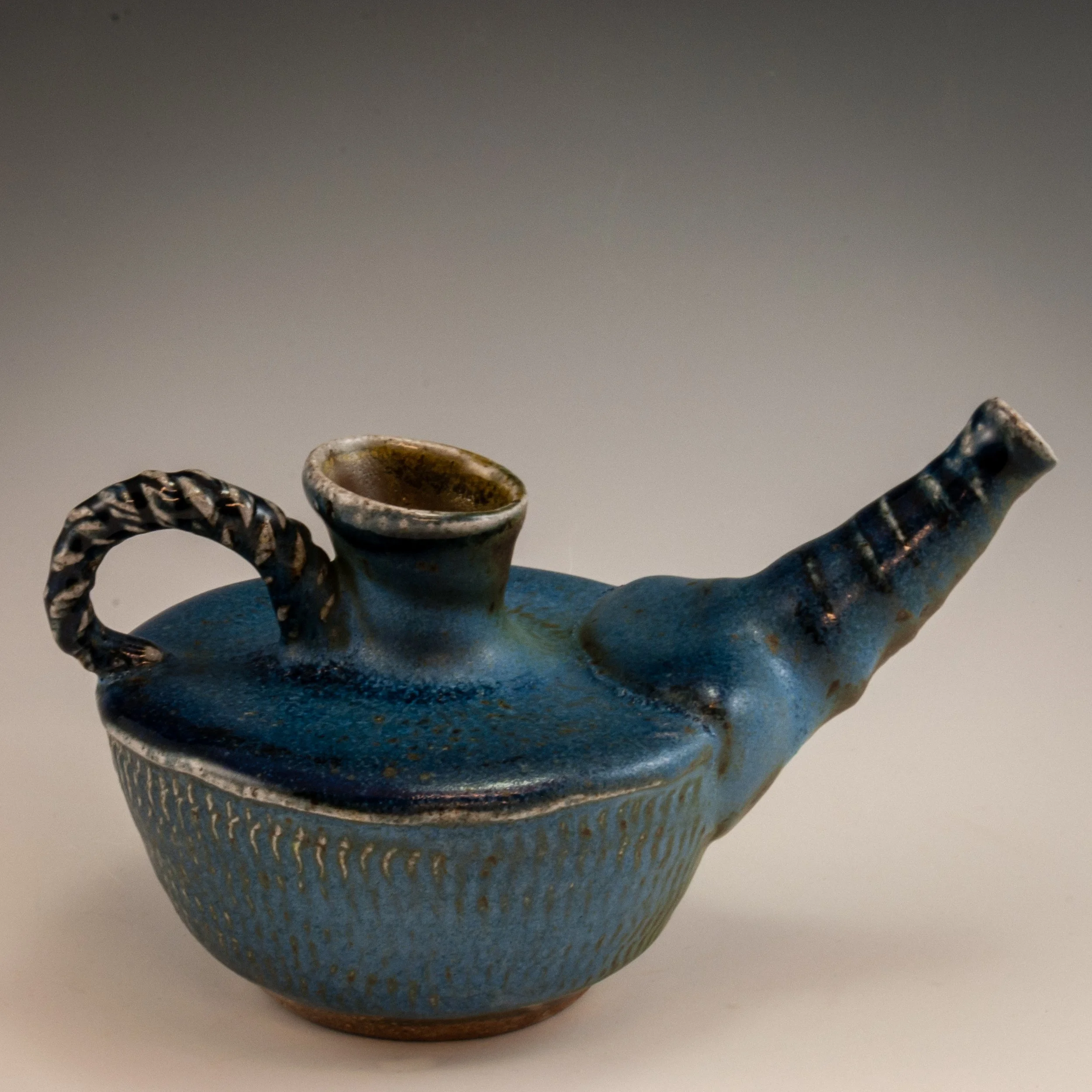A blue ceramic vessel with intricate textured patterns and two handles, one on each side.