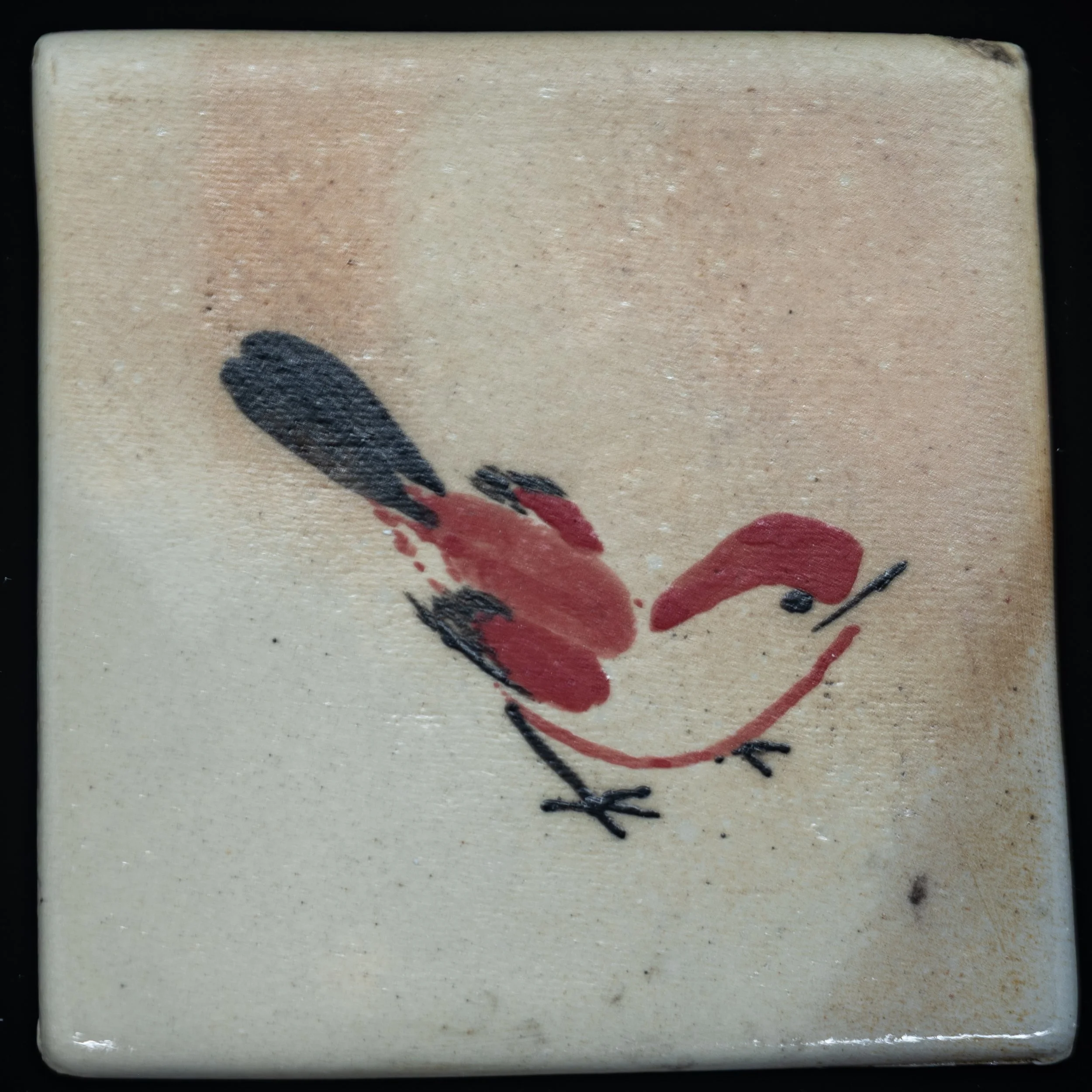 Close-up of a rectangular object with a beige surface featuring a black and red abstract design.