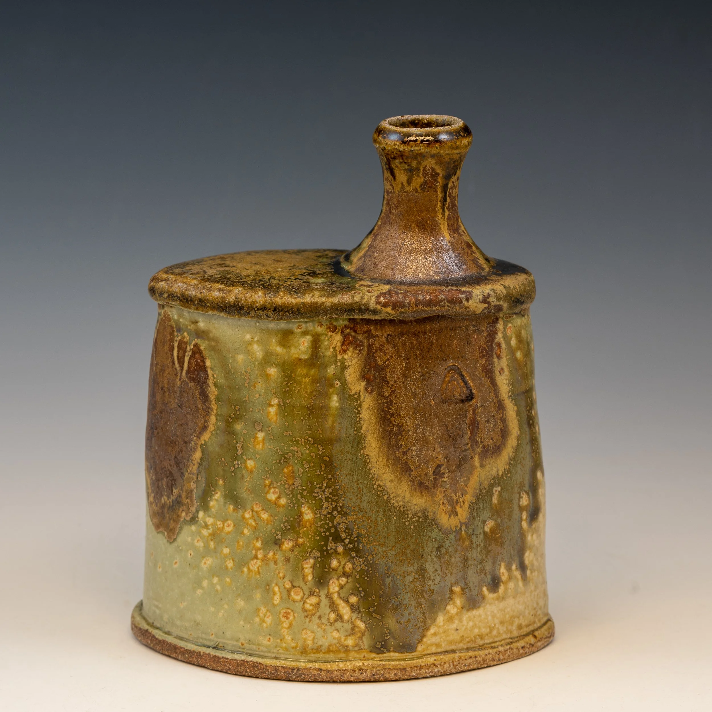 A ceramic vessel with a wide, rounded body and a narrower neck, featuring a textured, speckled glaze in earthy tones of brown, green, and gold.