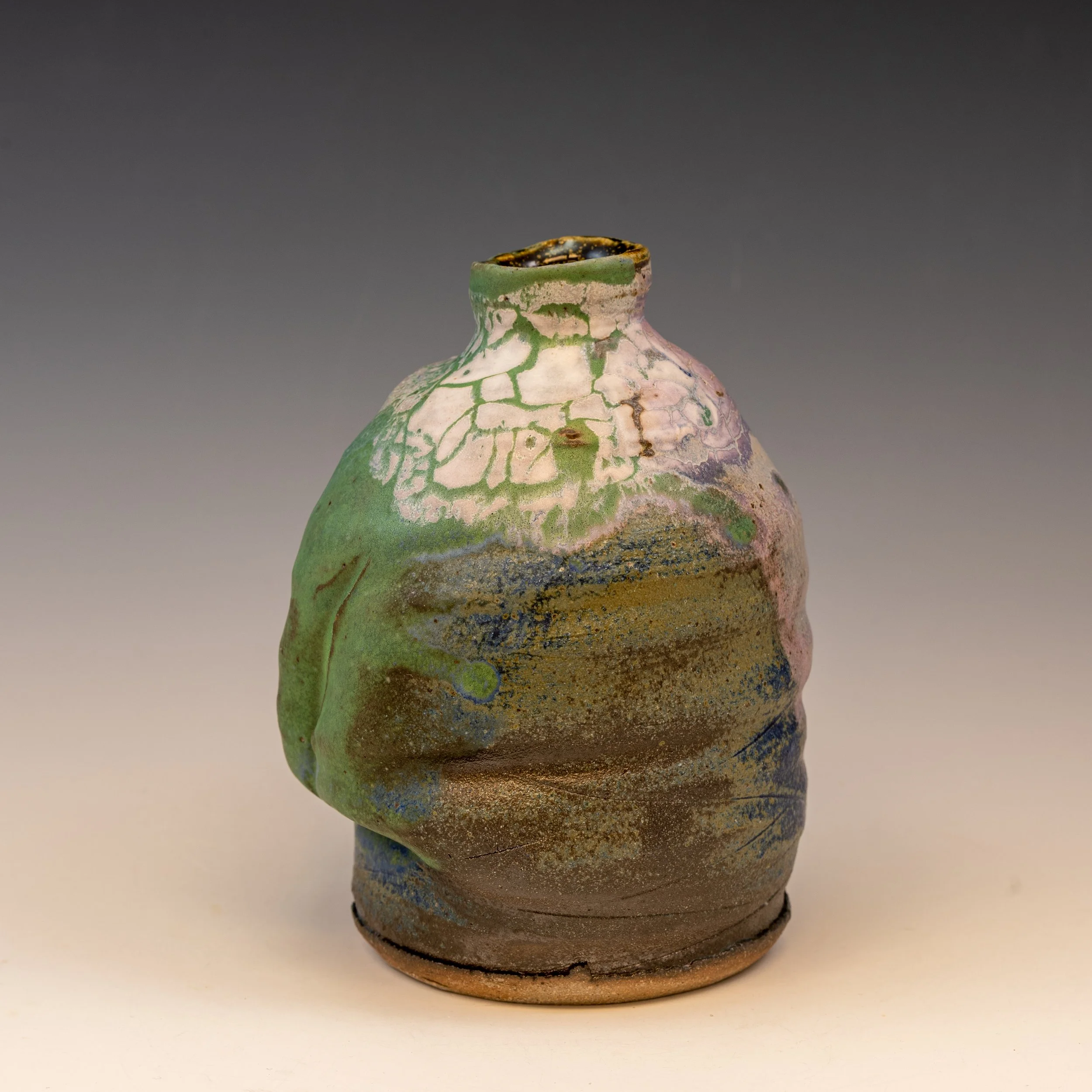A pottery vase with a narrow neck, decorated with a green and beige crackled glaze, set against a plain gradient background.