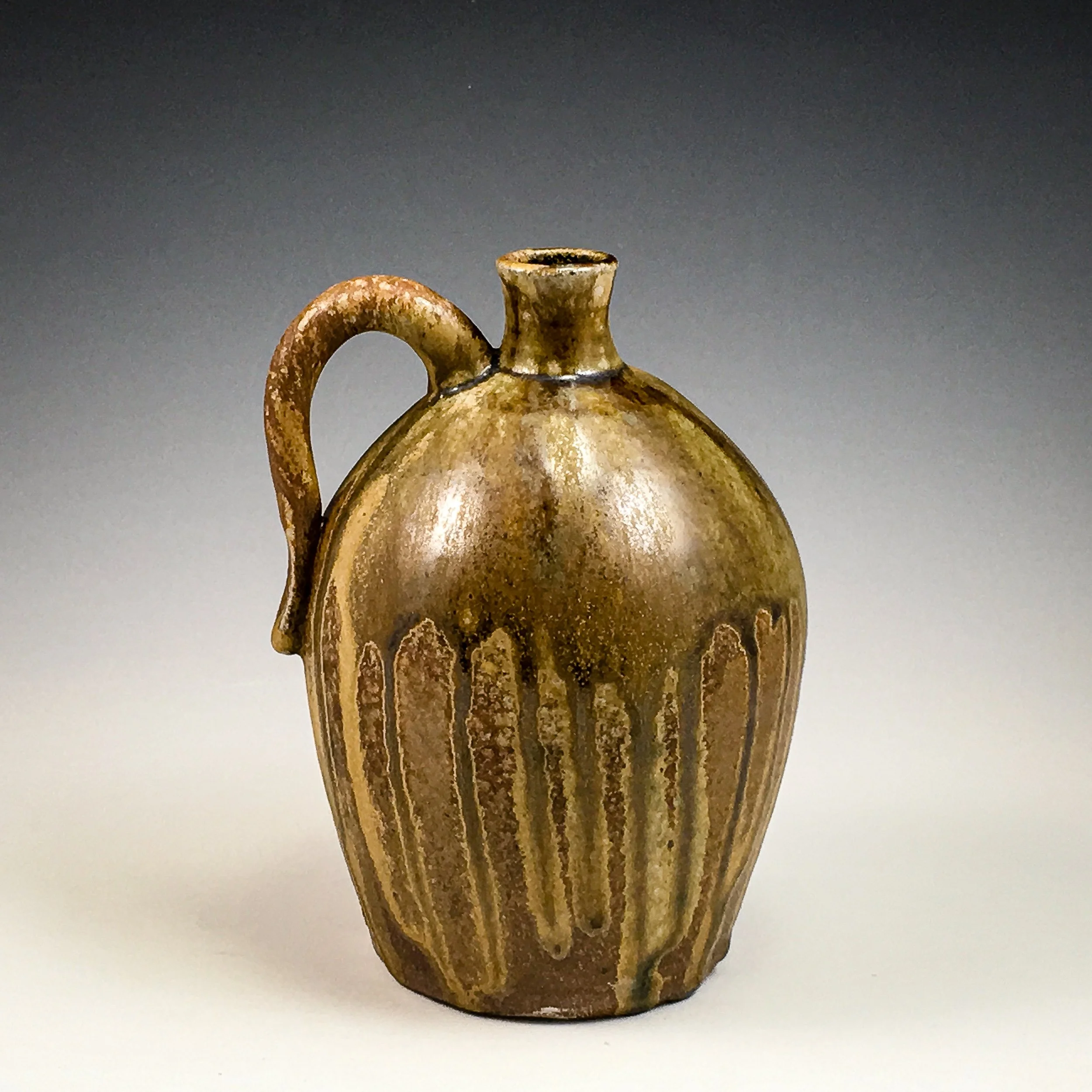 Ancient pottery vessel with wide body, narrow neck, and curved handle, decorated with vertical bands and motifs, placed on a plain surface against a dark background.