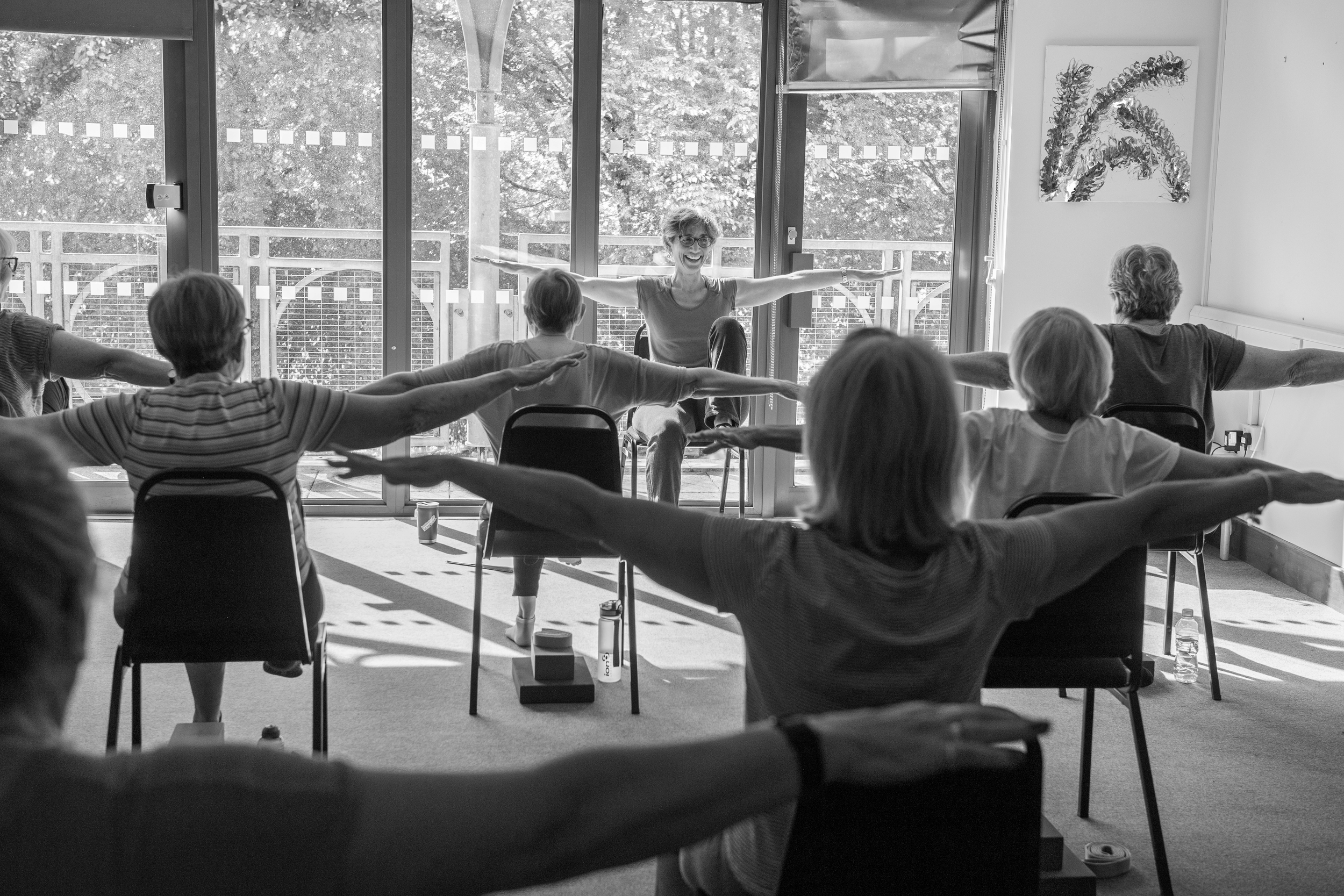 seniors in a fitness class seating on a chair with yoga teacher in East Grinstead West Sussex