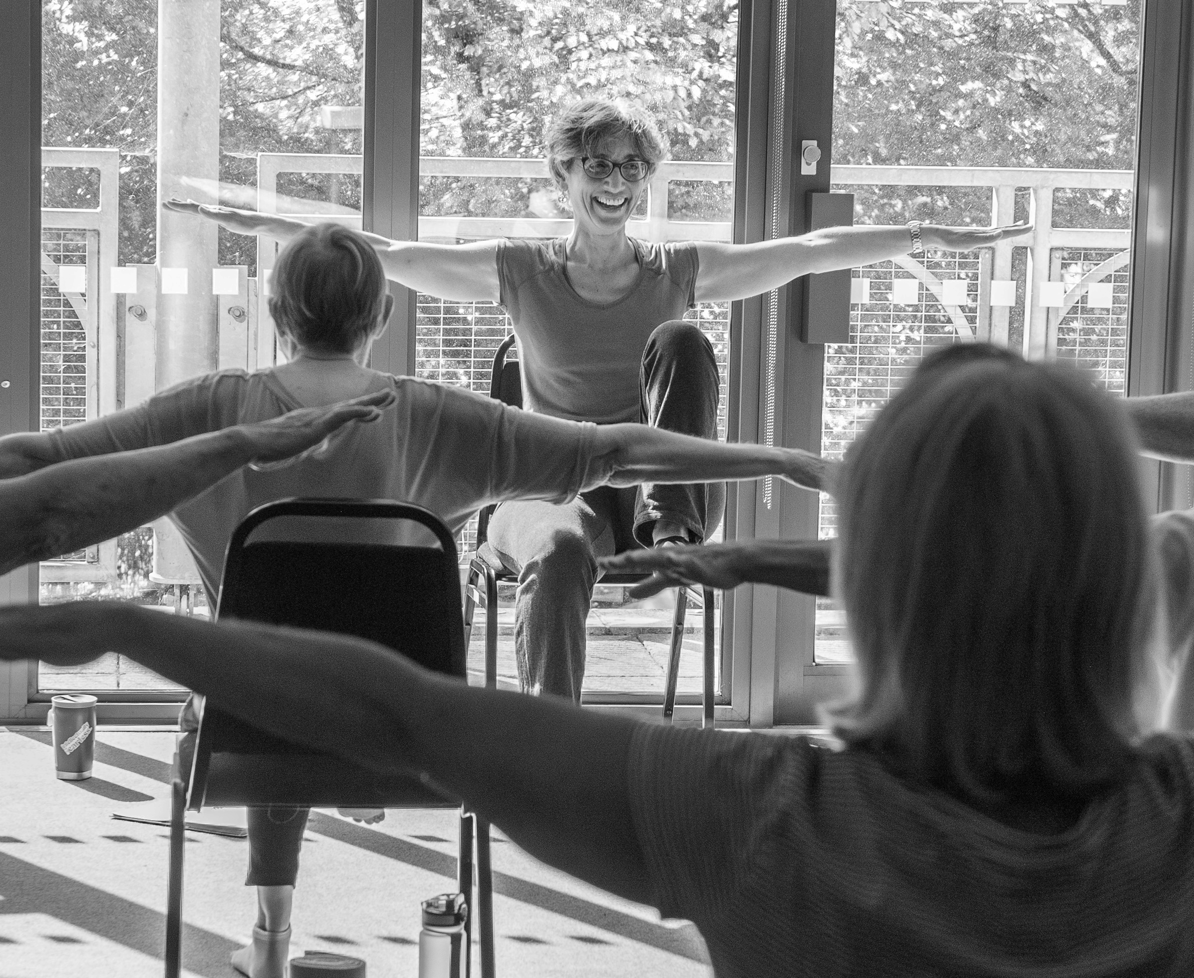 Older adults seating in a chair doing yoga