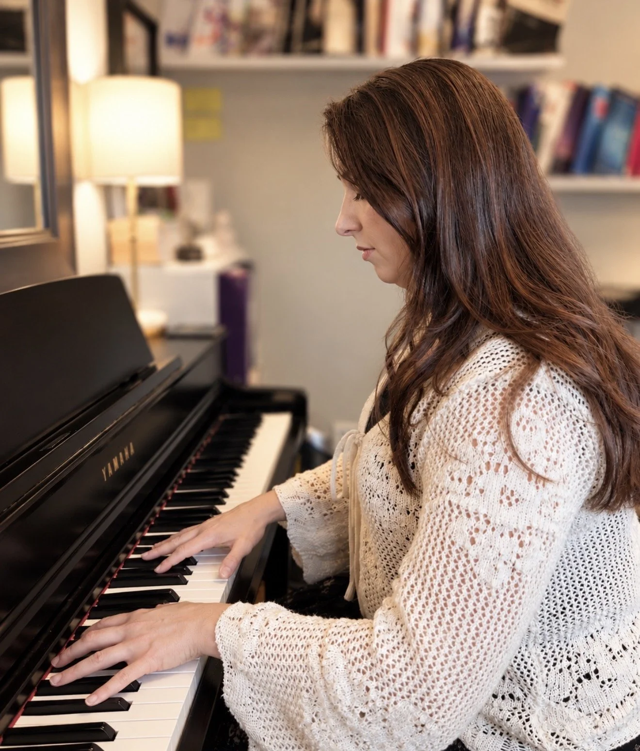 Rebecca Cypher playing a black yamaha piano in a music studio.