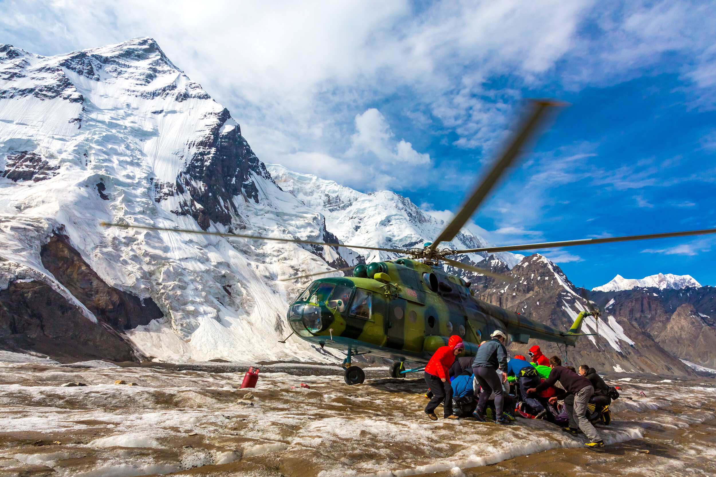 Helicopter Taking Off Ice Field of Massive Glacier and People Holding Luggage (Copy)