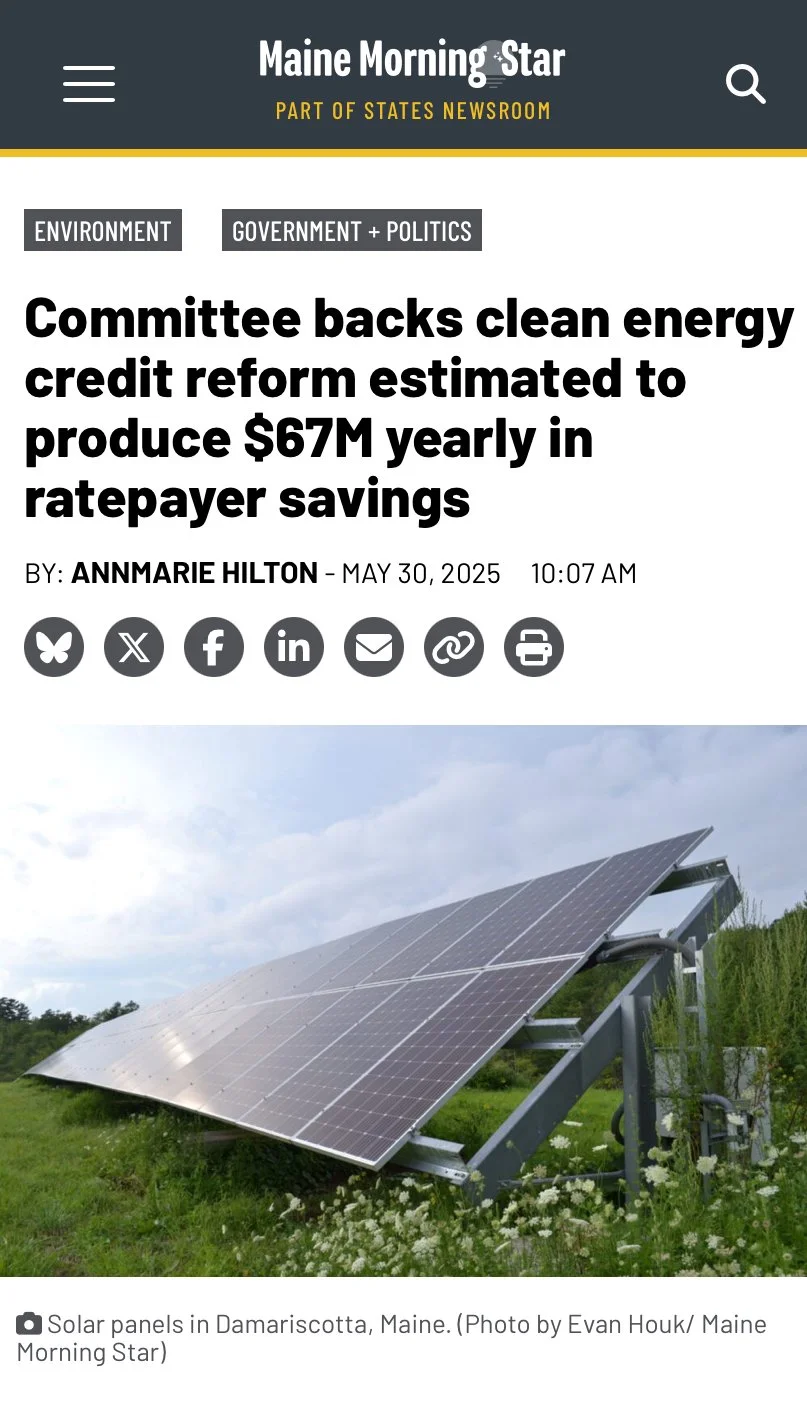 Solar panels in Damariscotta, Maine, installed on a grassy field with partly cloudy sky.