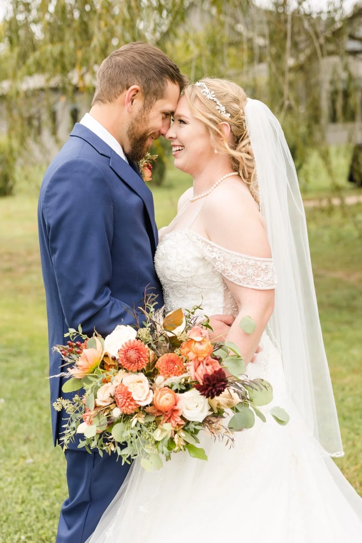 Bride and groom smiling with bouquet during outdoor wedding