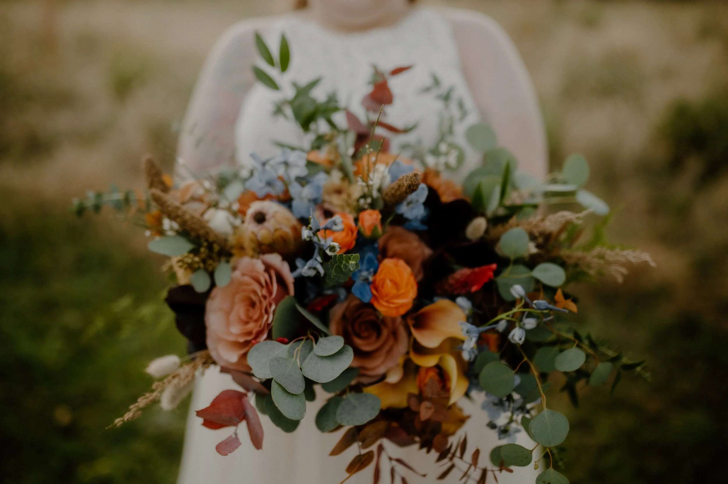 Bride holding a colorful bouquet with roses and greenery