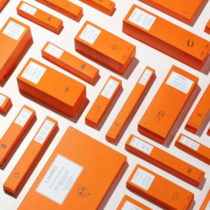 Multiple orange boxes of Chado incense arranged on a white surface.