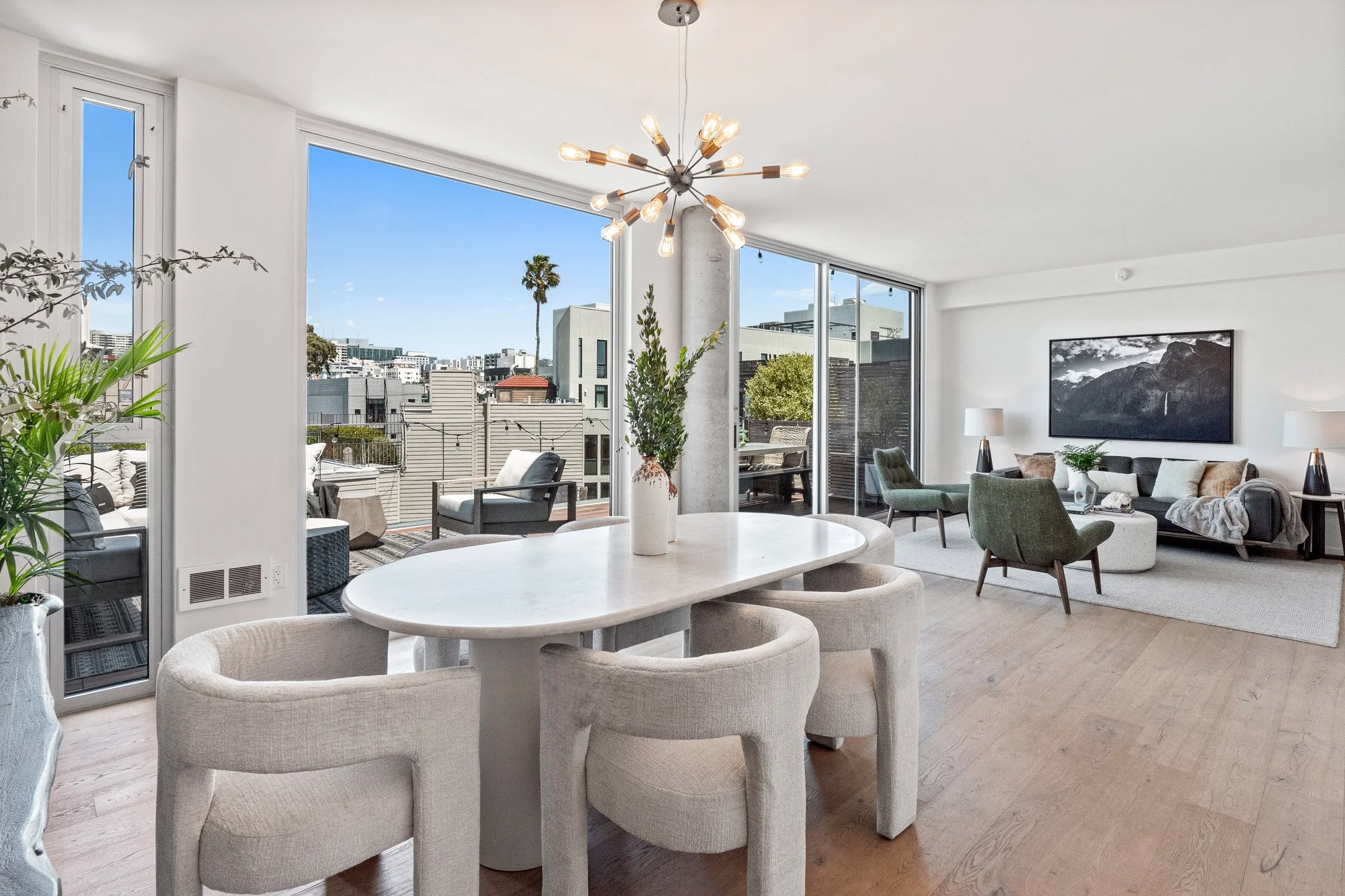 Modern living room and dining area with large windows showing cityscape and outdoor seating
