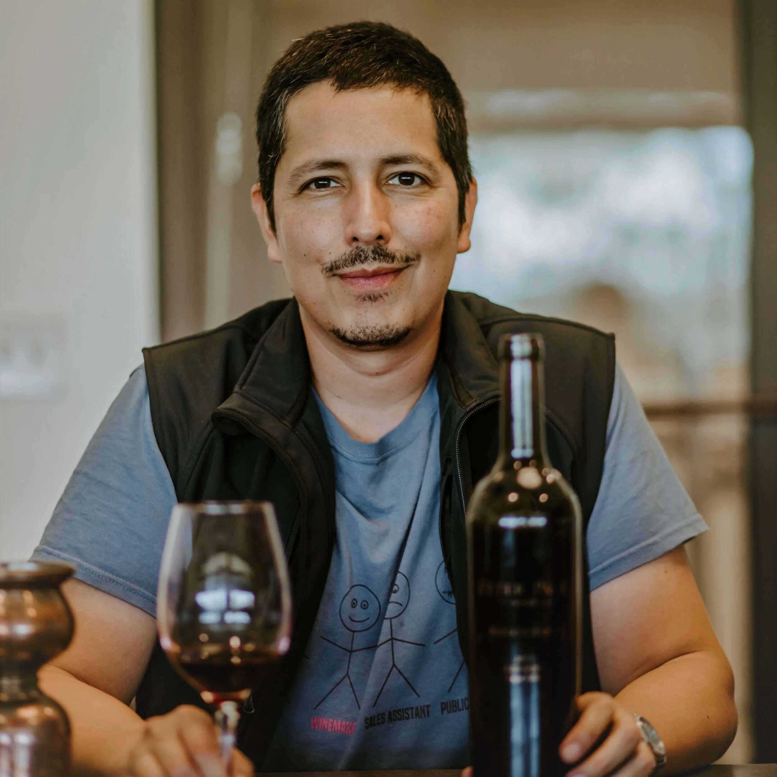 Martin Reyes holding a glass of wine and a win bottle, smiling