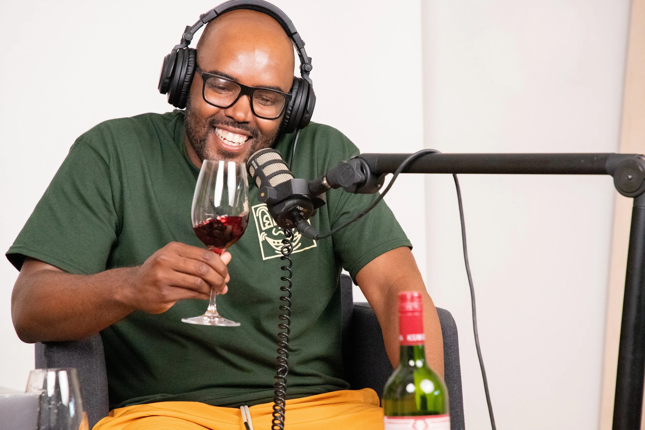 Podcaster smiling while swirling wine in a glass